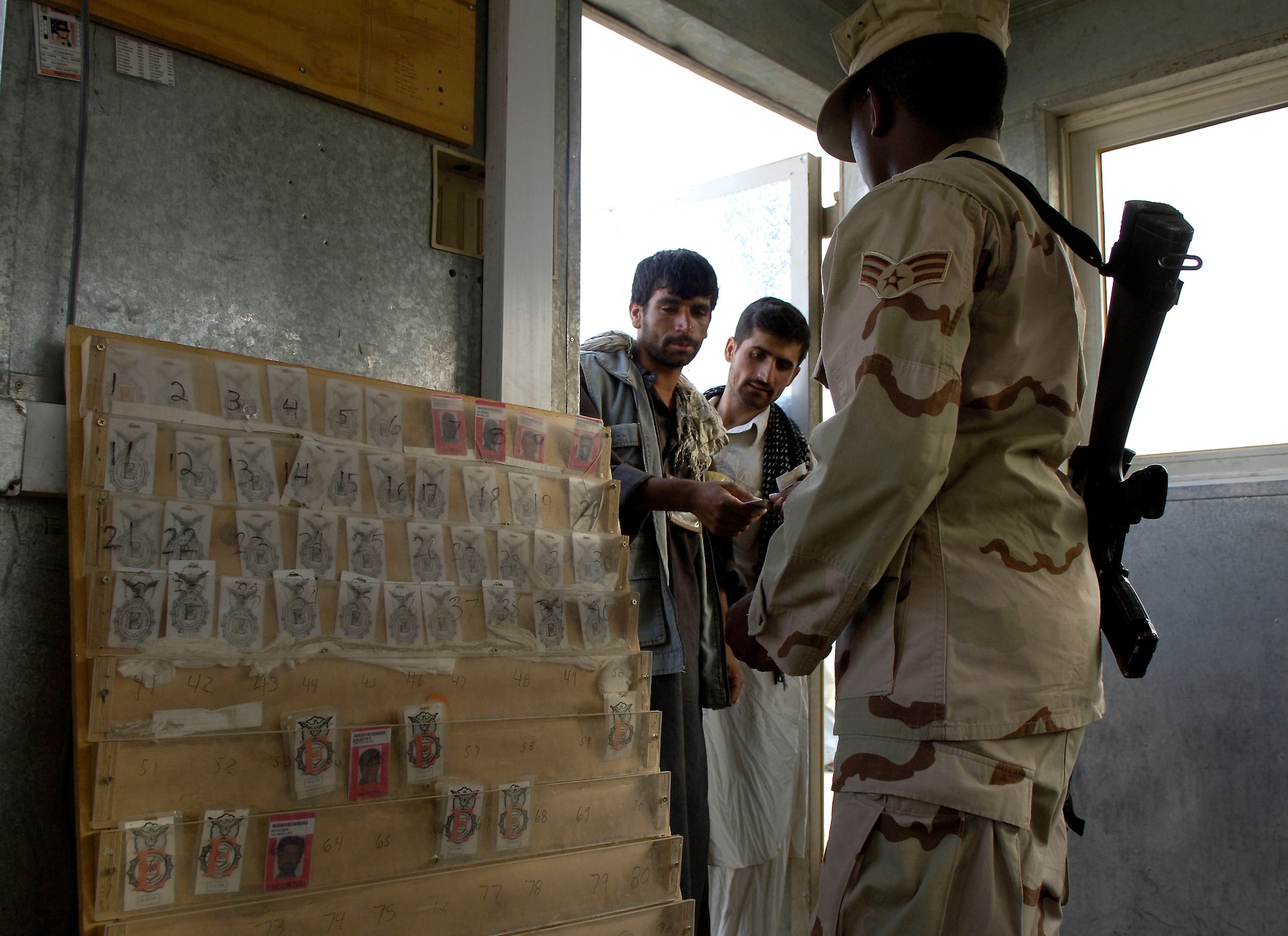 Senior Airman Raymond King takes a badge from a local national working on Bagram Air Base, Afghanistan, Aug 24, 2006.  The workers are employed by a contractor on the base and are escorted by Airmen while on the job.  The badges ensure each worker is accounted for.  Airman King is a force protection escort deployed from Dover Air Force Base, Del. (U.S. Air Force photo/Senior Airman Brian Ferguson)
