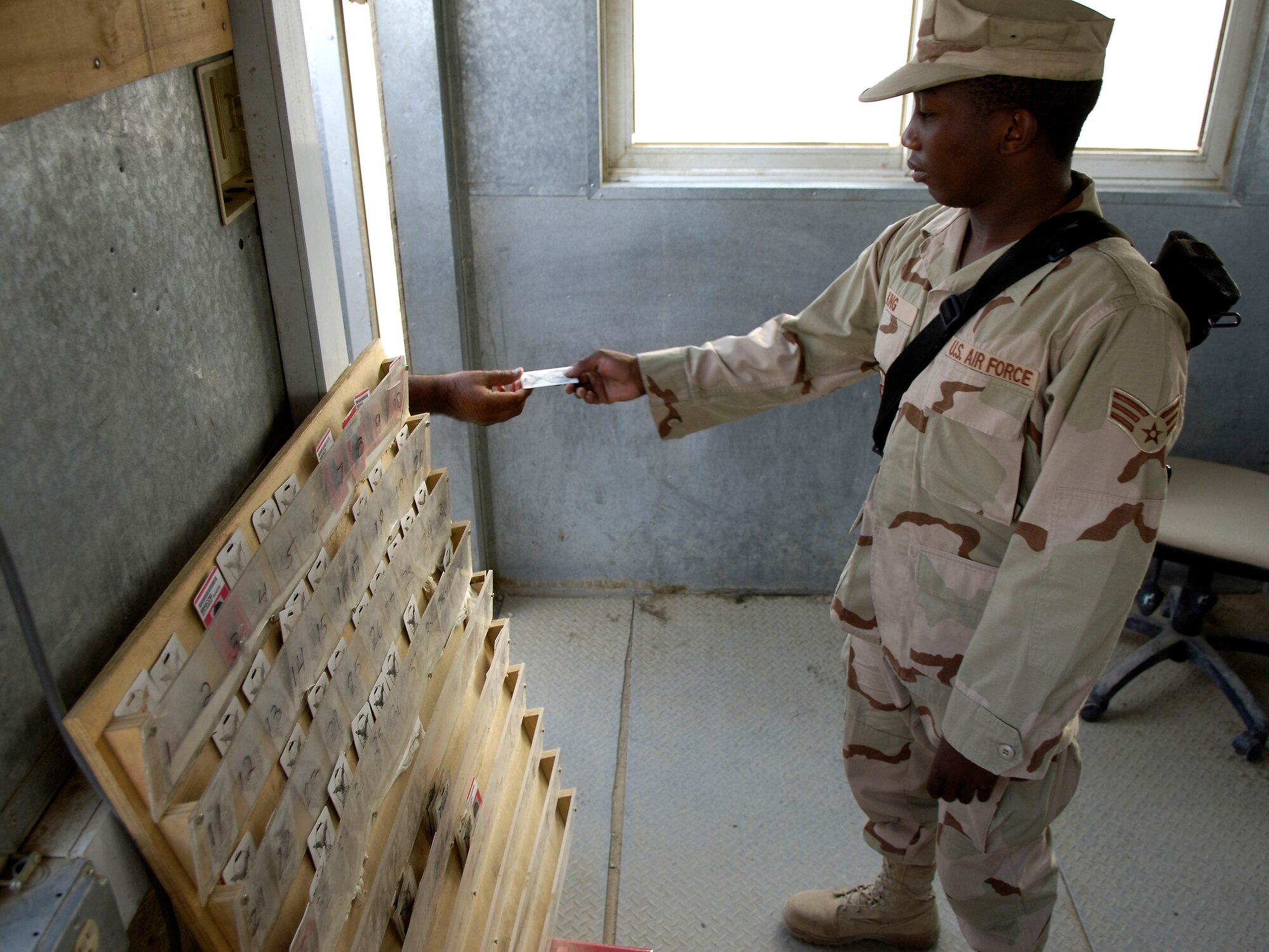 Senior Airman Raymond King takes a badge from a local national working on Bagram Air Base, Afghanistan, Aug 24, 2006.  The workers are employed by a contractor on the base and are escorted by Airmen while on the job.  The badges ensure each worker is accounted for.  Airman King is a force protection escort deployed from Dover Air Force Base, Del. (U.S. Air Force photo/Senior Airman Brian Ferguson)
