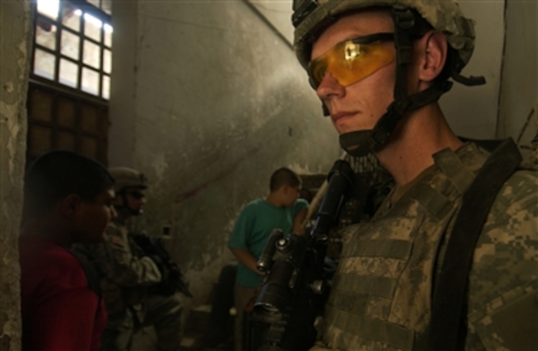U.S. Army Spc. Samuel Dumas secures the entrance of an Adhamiyah neighborhood apartment complex in Baghdad, Iraq, on Aug. 31, 2006.  Dumas' fellow soldiers from the 1st Battalion, 17th Infantry Regiment, 172nd Stryker Brigade Combat Team, are searching the apartments for weapons and other contraband items during a joint cordon and search mission by U.S. and Iraqi Army soldiers.  