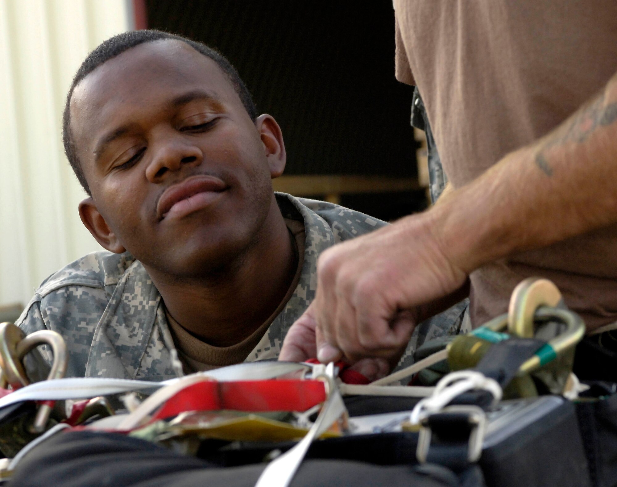 Specialist Denton Carter watches as a Department of Defense contractor shows him how to rig the new Joint Precision Air Drop System in Bagram Afghanistan Aug. 25, 2006. The system, going through operational testing here, is designed to deliver airdrop loads to troops on the ground with more precision than the normal airdrop system.  Spc. Carter is a parachute rigger with the 647th Quartermaster Detachment.  
(U.S. Air Force photo/Senior Airman Brian Ferguson)
