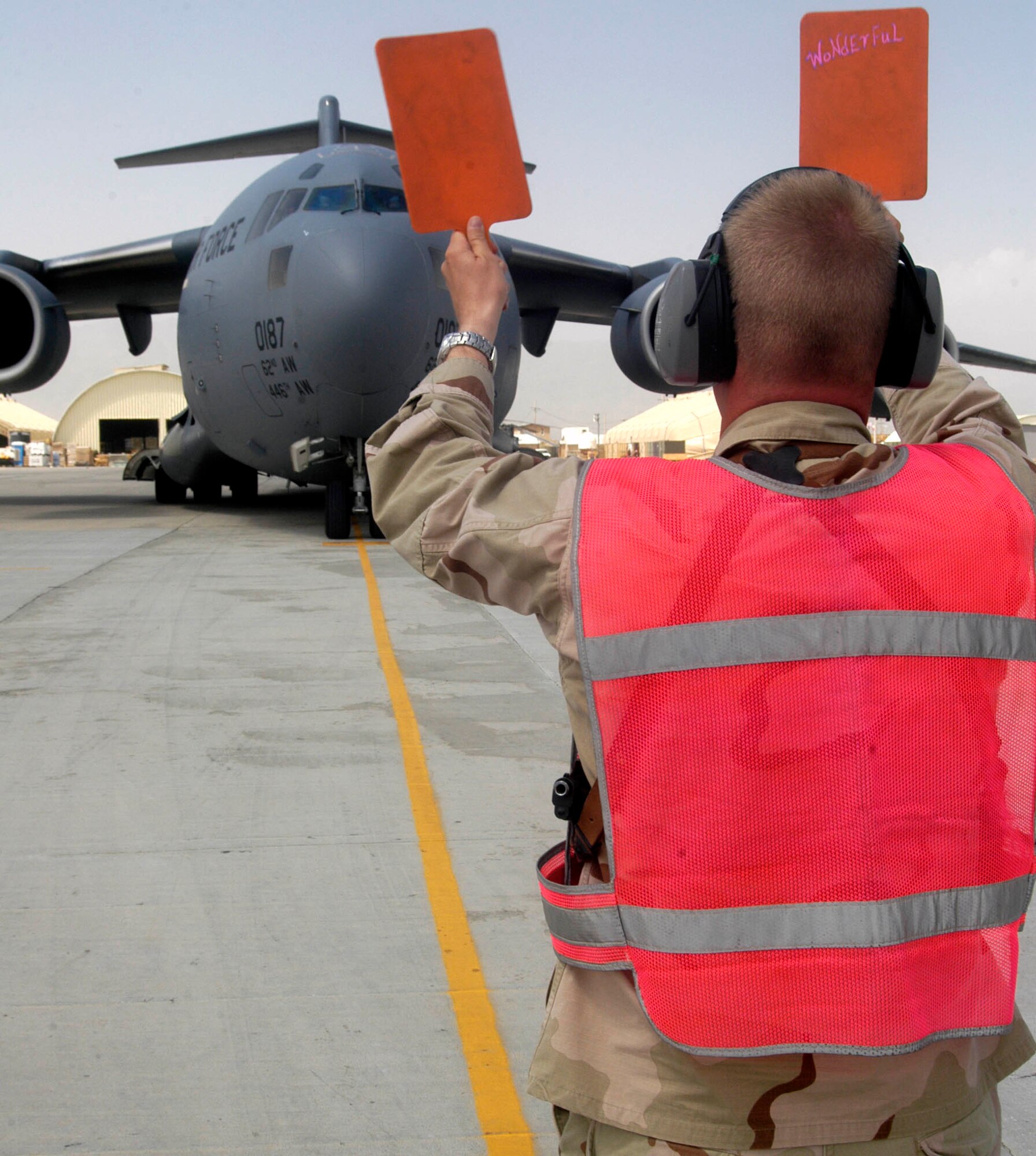 Maj. Timothy Coger uses paddles to direct a C-17 into its parking spot Sept. 2, at Bagram Airfield, Afghanistan.  The major is the commander of the 455th Expeditionary Maintenance Squadron at Bagram.  The C-17, from the 62nd Airlift Wing, McChord Air Force Base, Wash., was the 2,000th transient aircraft to land at Bagram for Air Expeditionary Force one and two, which began May 7, for the transient alert team here.  Two-thousand planes equates to an average of almost 17 aircraft transiting Bagram per day.  Transient aircraft are those that arrive at Bagram to unload, or load, cargo and passengers to support Operation Enduring Freedom, then take off again and are not assigned here. Major Coger is deployed to Bagram from Spangdahlem Air Base, Germany.  (US Air Force photo/Maj. David Kurle)