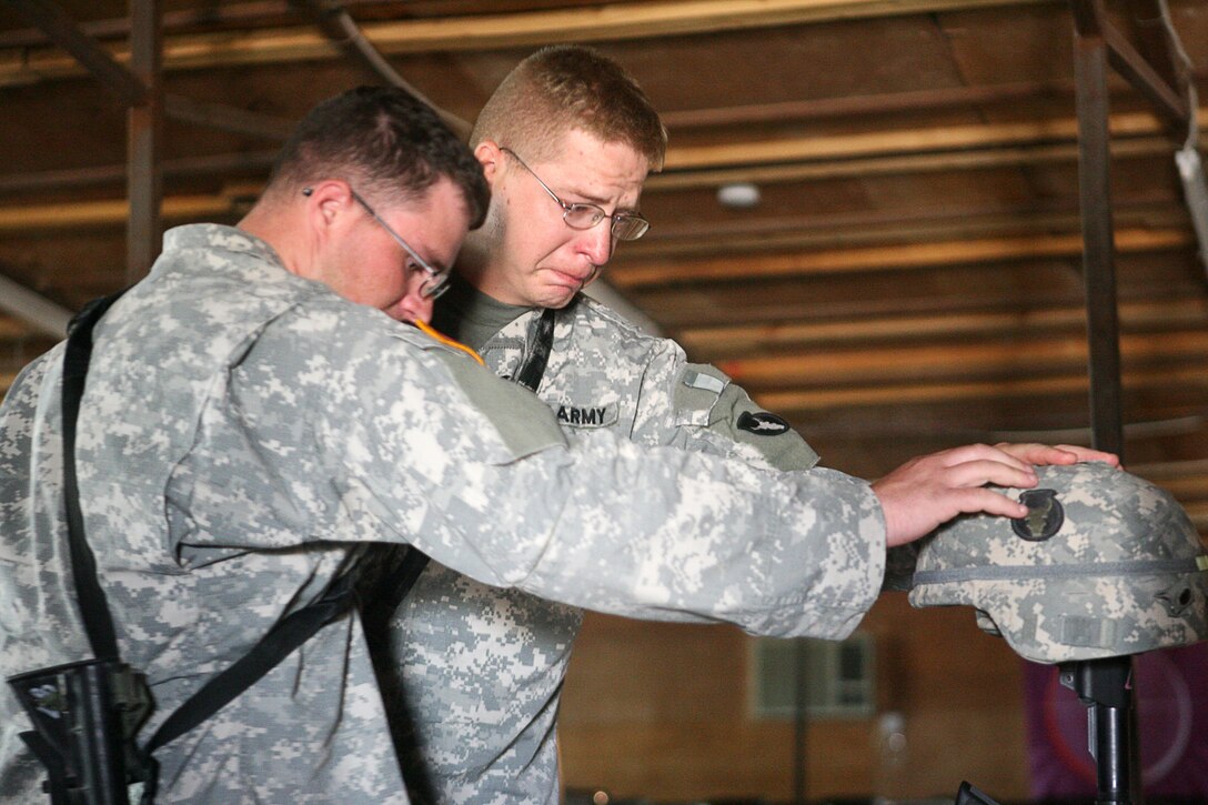 Soldiers with Able Company, 2nd Battalion, 136th Infantry Regiment, show emotion while they pay their respects during a memorial ceremony held for Army Staff Sgt. Joshua R. Hanson, a fire team leader with Able Company, at Mainside Chapel here September 4. The Dent, Minn., native lost his life August 22, 2006 from wounds sustained while engaging in operations in the restive Al Anbar province. The memorial consisted of the playing of our national anthem, prayer; a scripture read by Justin D. Knopf, a 24-year-old squad leader from Detroit Lakes, a photo slide show, a 21- shot rifle salute and the playing of ?Taps?.  An inverted M-16A2 rifle was placed in Hanson?s homage, with a Kevlar helmet resting on top.  Engraved identification tags and a crucifix hung from the rifle?s pistol grip. Immediately in front, an empty pair of boots was positioned, while behind the display, the national ensign and battalion colors were displayed. Along the sides were two ammunition cans containing keepsakes from fellow soldiers.  The battalion, an Army National Guard unit out of Detroit Lakes, Minn, is currently attached to 1st Marine Logistics Group (Fwd).