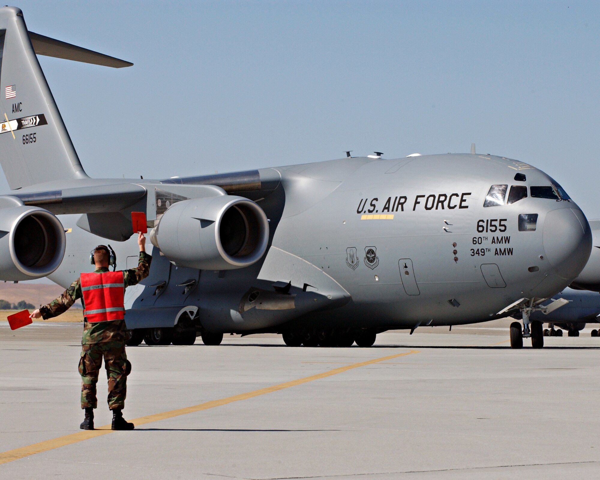 C-17 piloted by Brigadier Gen. Buddy Reed taxis in as crewchief Staff Sgt. Jeffrey Eckert directs the aircraft to its parking location at Travis AFB. The arriving C-17 is the second of thirteen that will be stationed at Travis. Photo by David W. Cushman GS-11