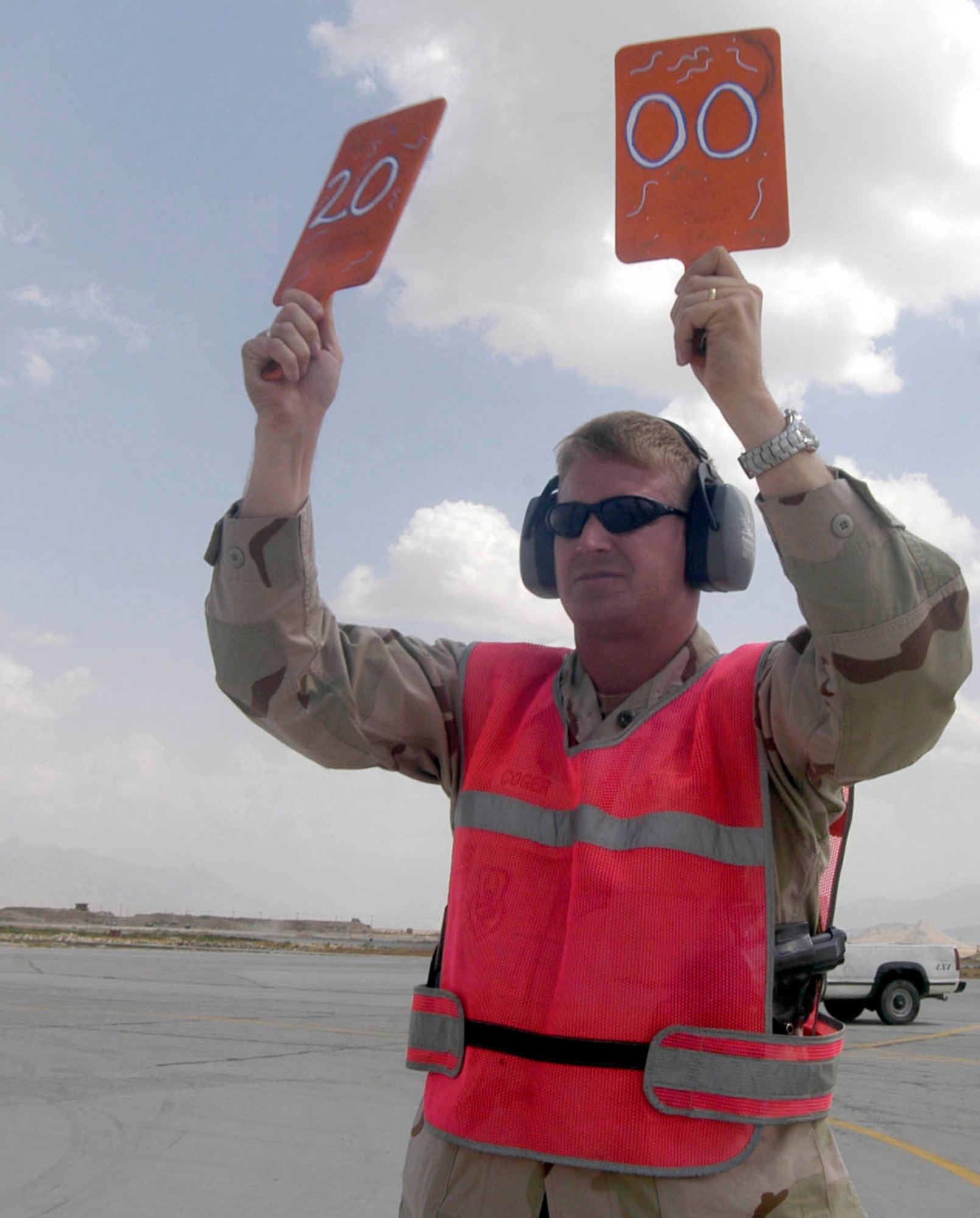 Maj. Timothy Coger uses specially marked paddles to direct a C-17 Globemaster III into its parking spot at Bagram Air Base, Afghanistan, Sept. 2. The C-17, from the 62nd Airlift Wing at McChord Air Force Base, Wash., was the 2,000th transient aircraft to land at Bagram for Air Expeditionary Forces 1 and 2, which began May 7. That number equates to an average of 17 aircraft transiting Bagram daily. Major Coger is the commander of the 455th Expeditionary Maintenance Squadron at Bagram and is deployed from Spangdahlem Air Base, Germany. (U.S. Air Force photo/Maj. David Kurle) 
