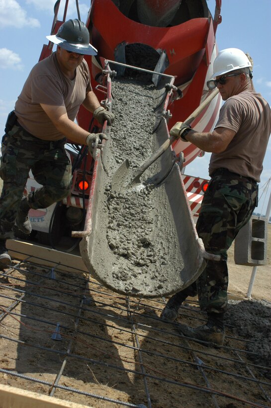 Air Force Reserve Staff Sgt. Lonnie Williams and Master Sgt. Victor Rice, both 301st Civil Engineer Squadron, fill a frame with concrete. The pad is being constructed to hold the wing alert facility's stand-alone generator. (U.S. Air Force Photo/Tech. Sgt. Julie Briden-Garcia)