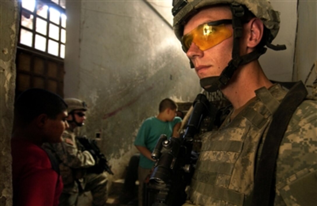 U.S. Army Spc. Samuel Dumas secures the entrance of an Adhamiyah neighborhood apartment complex in Baghdad, Iraq, Aug. 31, 2006.  Dumas' fellow soldiers from the 1st Battalion, 17th Infantry Regiment, 172nd Stryker Brigade Combat Team, are searching the apartments for weapons and other contraband items during a joint cordon and search mission by U.S. and Iraqi Army soldiers.  