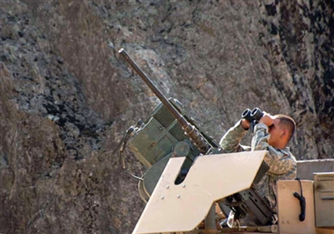 U.S. Army Spc. David Mendez, from Alpha Company, 3rd Squadron, 71st Cavalry Regiment, 3rd Brigade, 10th Mountain Division, scans the ridgelines for possible enemy movement and rocket-propelled grenade positions at the Kamdesh Provincial Reconstruction Team Base in the Kunar province of Afghanistan, Aug. 29, 2006. 