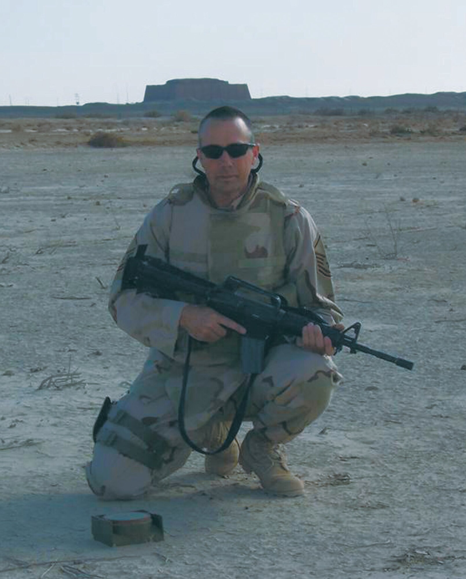 U.S. Air Force Reservist Master Sgt. Eric Wass kneels in front of an anti-tank mine, whiich he had just disarmed during an ordinance sweep in Iraq. (U.S. Air Force Photo)