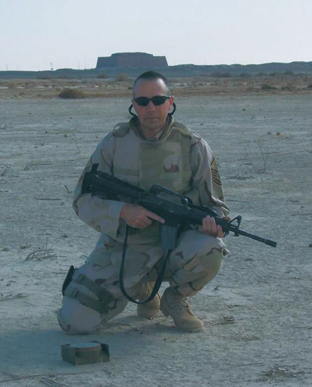 U.S. Air Force Reservist Master Sgt. Eric Wass kneels in front of an anti-tank mine, whiich he had just disarmed during an ordinance sweep in Iraq. (U.S. Air Force Photo)