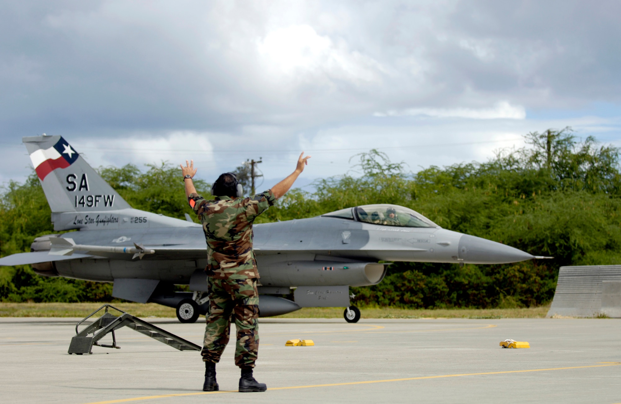 Master Sgt. Roy Rae marshals an F-16 Fighting Falcon to its parking spot at Hickam Air Force Base, Hawaii, Sept. 6. Six F-16s and crews from the Texas Air National Guard's 149th Fighter Wing are participating in Exercise Sentry Aloha. The exercise brings dissimilar combat assets to Hickam to train with the Hawaii Air National Guard's 199th Fighter Squadron. (U.S. Air Force photo/Tech. Sgt. Shane A. Cuomo)