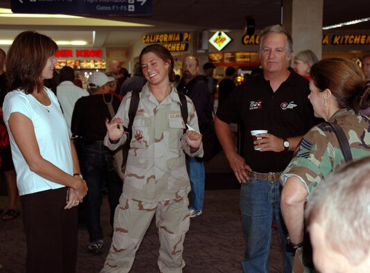 Senior Airman Taylor Debel, 934th Logistics Readiness Squadron, reuinites with her parents at Minneapolis St. Paul International Airport as Chief Master Sgt. Jan Dalton, 934th Airlift Wing command chief, looks on. Airman Debel was one of five LRS members deployed for more than six months to a forward operating location in support of Operation Iraqi Freedom.