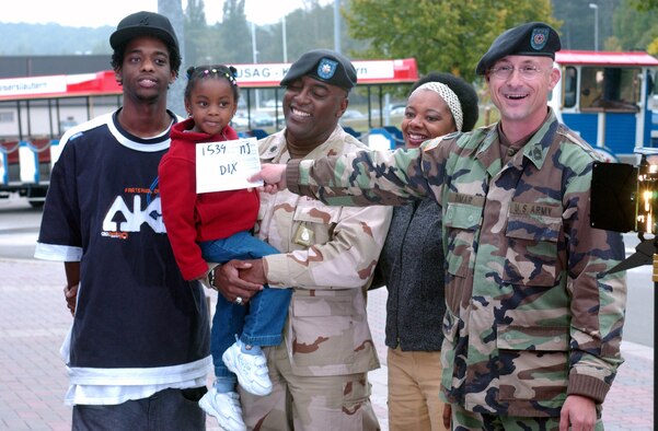 Sgt. 1st Class Peter Rimer, from the Army and Air Force Hometown News Service European team, gives the cue for the first take of Lt. Col. Richard Dix and his family (left) J.R., Chandler and wife, Cynthia, during last year’s Hometown News Holiday Greetings at the Vogelweh Commissary. Photo by Chrisine June