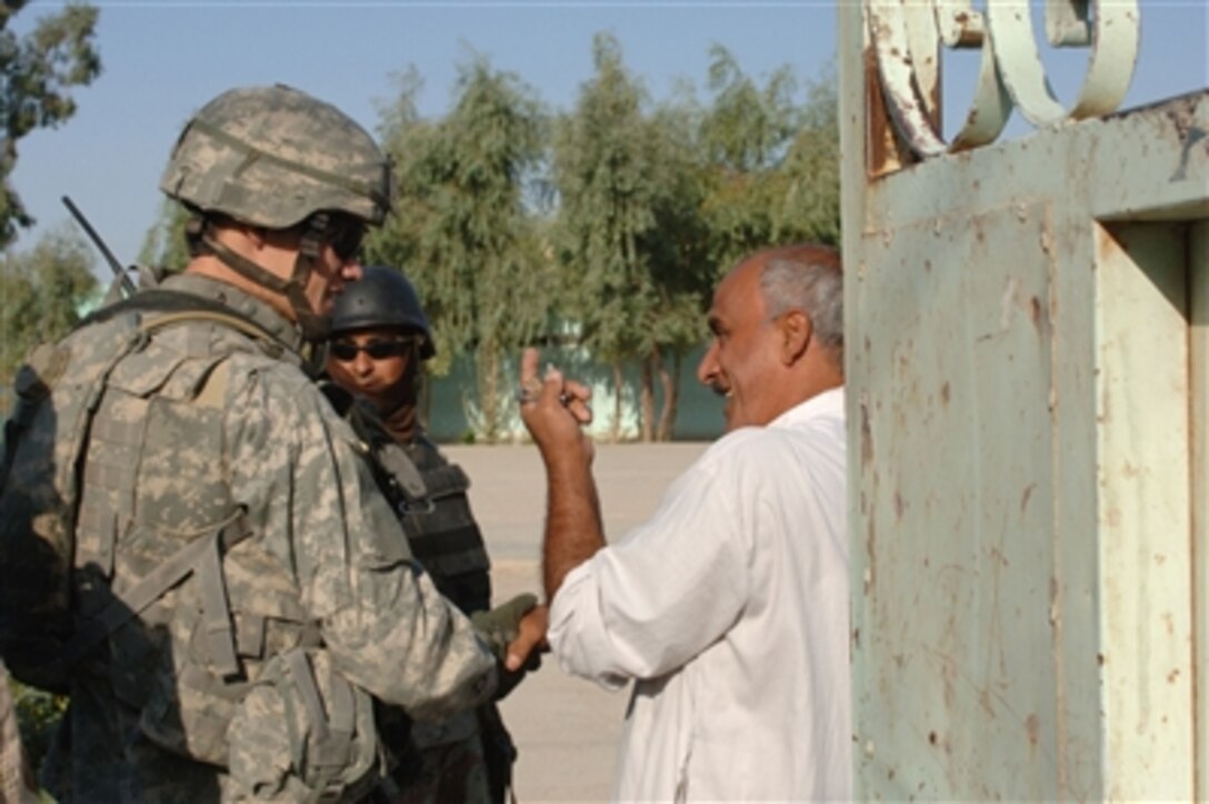 A U.S. Army soldier from the 2nd Brigade Combat Team, 1st Armored Division speaks with the man in charge of a school before searching the school for contraband weapons in Dinah, Baghdad, Iraq, on Sept. 1, 2006.  
