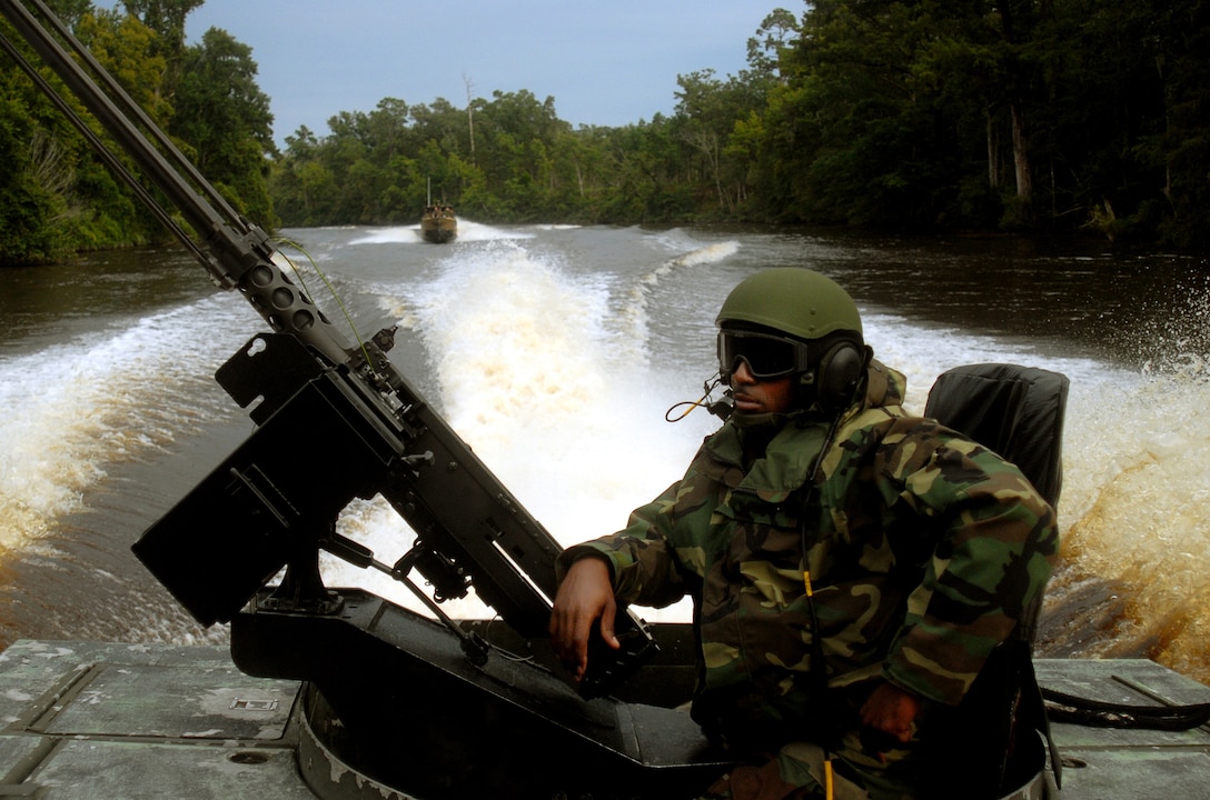 MARINE CORPS BASE CAMP LEJEUNE, N.C. - Petty Officer 2nd Class Tyrone Cole, student participating in the culminating exercise of the Riverine Coxswain's and Boat Captain's Course, casually scans the vegetation as his riverine assault craft makes its way along the Cape Fear River Sept. 6. Sixty sailors from various active duty units participated in the final exercise conducted by the Marines with Special Missions Training Center here Sept. 6-14 in preparation for the Navy's take over of Marine Corps river operations in Iraq next year. (Official U.S. Marine Corps photo by Lance Cpl. Brandon R. Holgersen)(released)