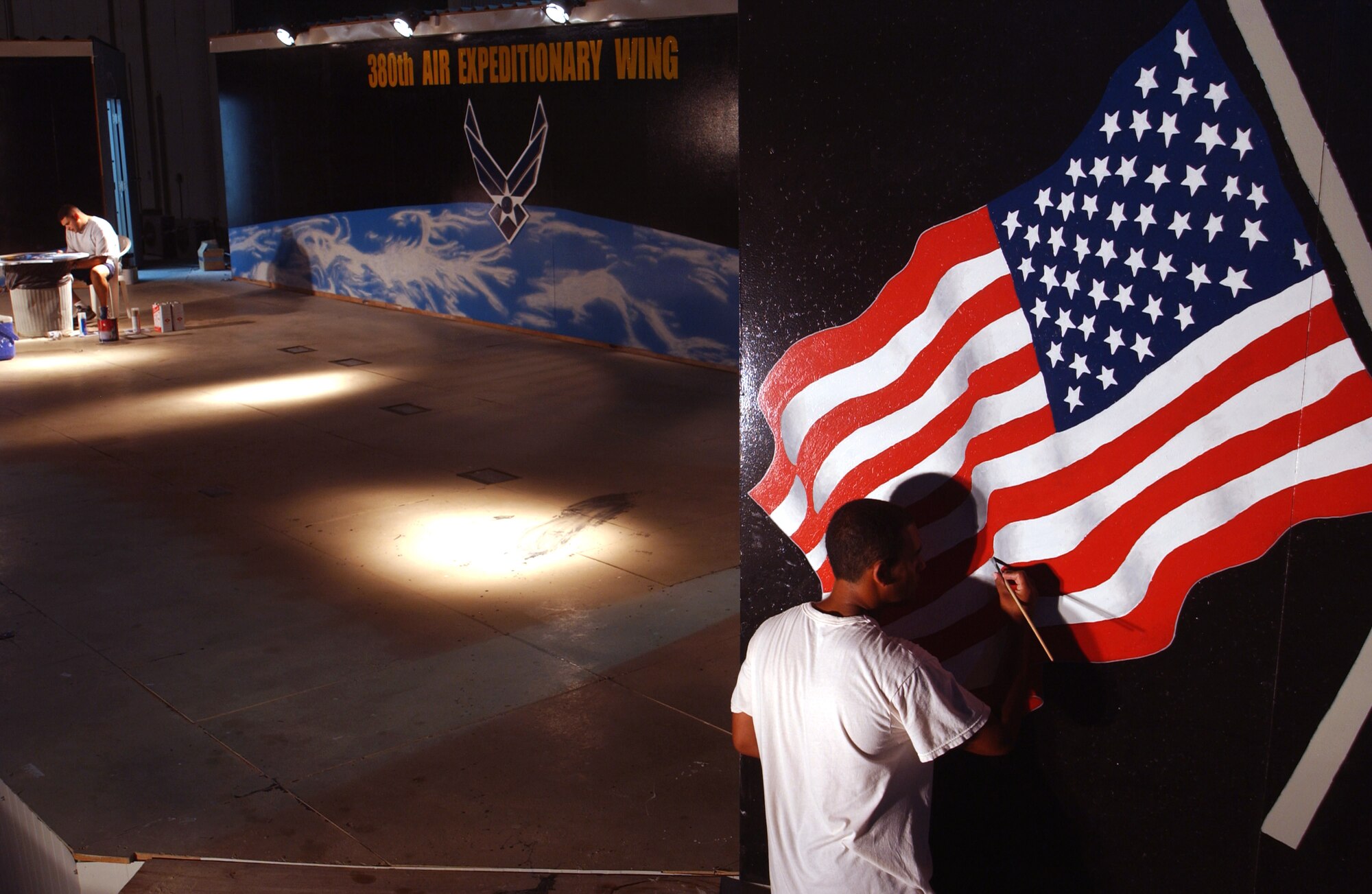Master Sgt. Ray Naranjo and Senior Airman Osvaldo Ros-Henriquez put final touches on the design of a stage for the 380th Expeditionary Wing at a forward-operating base in Southwest Asia Sept. 7. Both Airmen were part of a group who won a design contest after the stage was built. The work, which includes plywood shields of the wing and U.S. Central Command Air Forces crest, took about three weeks to complete. Sergeant Navanjo and Airman Ros-Henriquez are assigned to the 380th Expeditionary Civil Engineer Squadron. (U.S. Air Force photo/Master Sgt. Jason Tudor) 