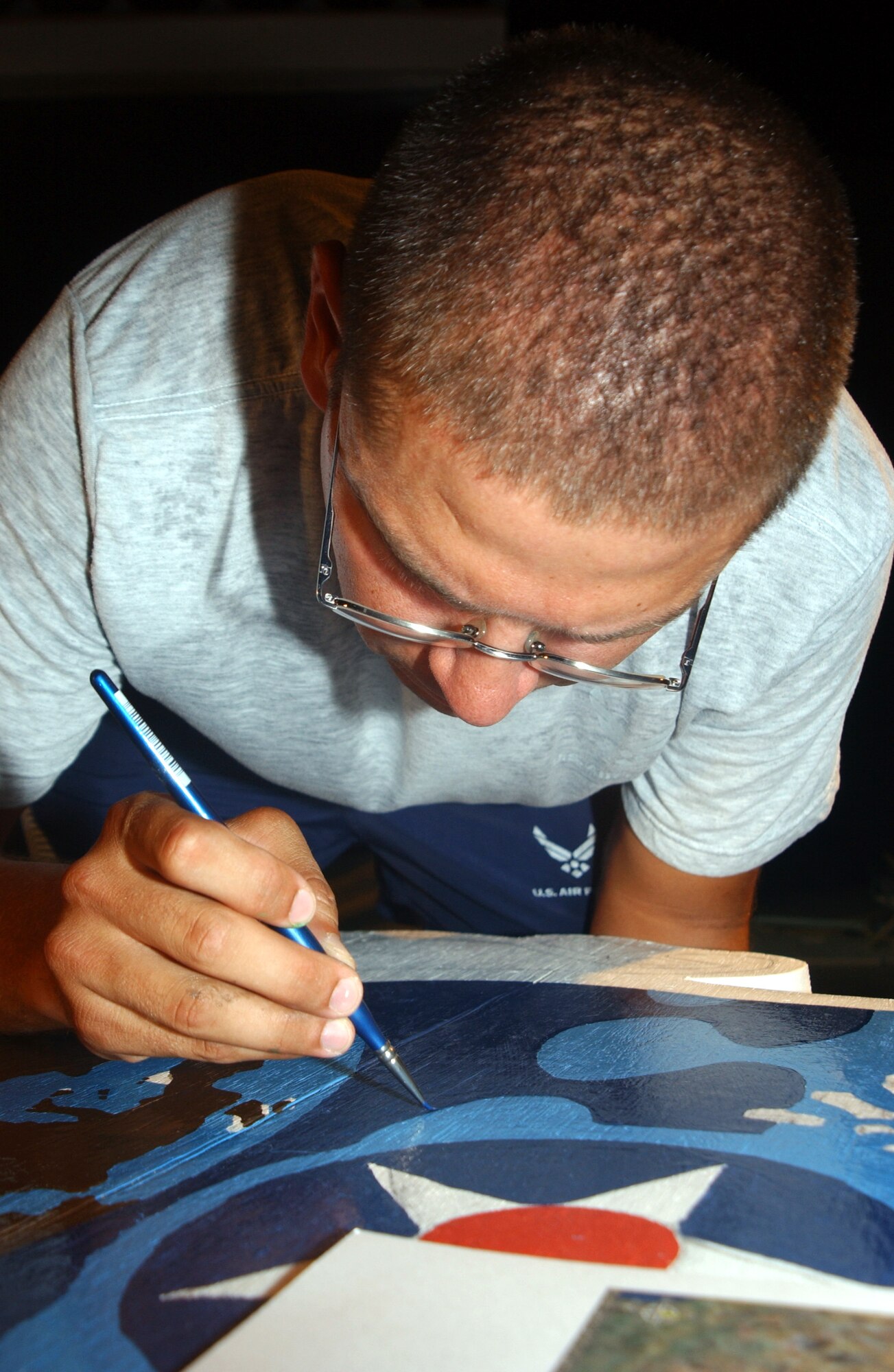 Airman 1st Class Rodrigo Trevino paints details on a plywood U.S. Central Command Air Forces crest Sept. 7, part of a design for a stage recently constructed for the 380th Expeditionary Wing at a forward-operating base in Southwest Asia. Airman Trevino was part of a group of people who won a design contest after the stage was built. The work, which includes the CENTAF and wing crest, took about three weeks to complete. Airman Trevino is assigned to the 380th Expeditionary Civil Engineer Squadron. (U.S. Air Force photo/Master Sgt. Jason Tudor) 