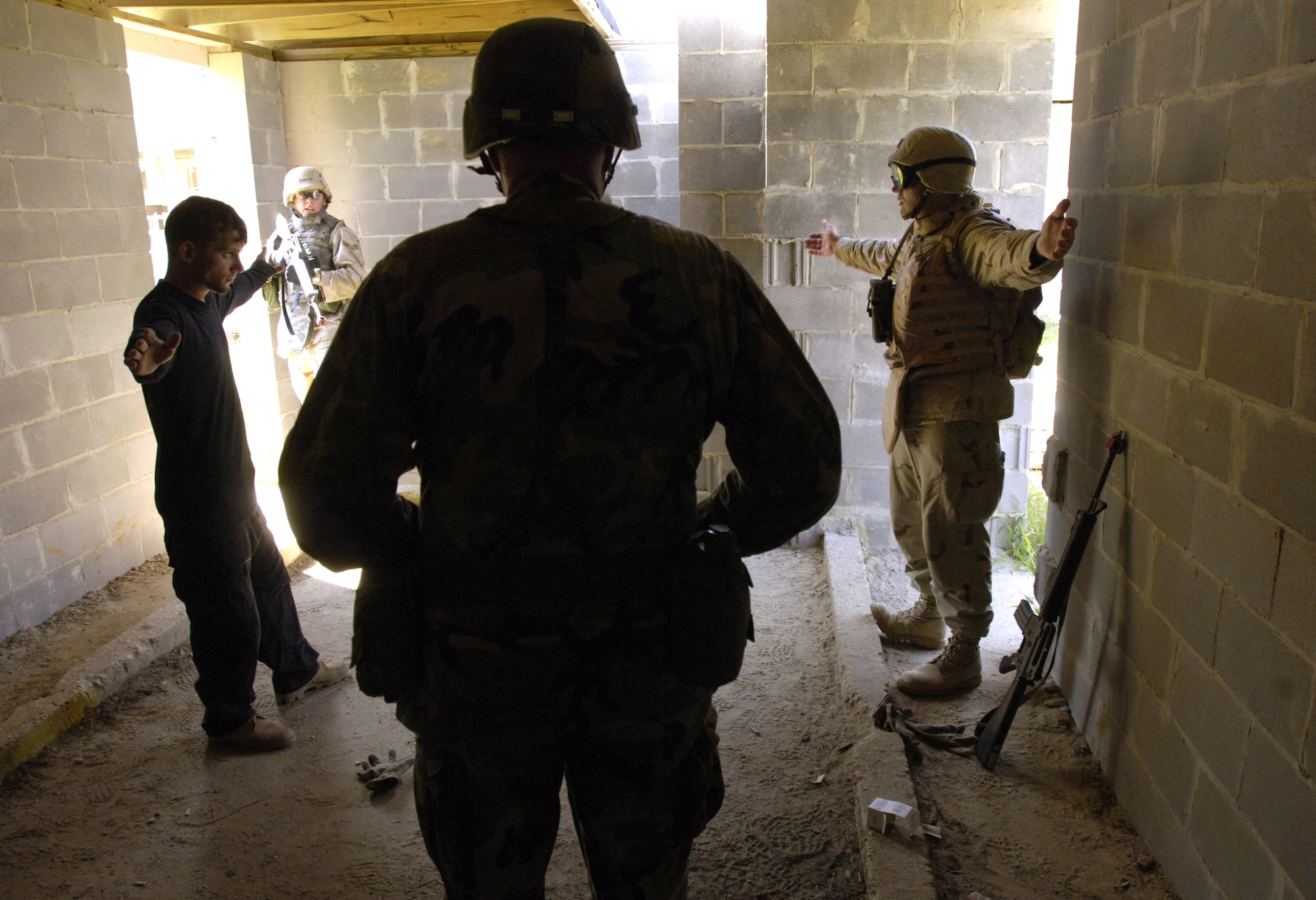 Capt. John Clark (right) and Senior Amn. Jeremy Hofstetter prepare to conduct a search of a "suspect" while Army Sgt. 1st Class Daniel Criddle (foreground) offers instruction and evaluation Sept. 2 during a course on urban warfare at Camp Shelby, Miss.  Camp Shelby is one of several Army installations providing training to military personnel preparing to deploy to Southwest Asia.  (U.S. Air Force photo/Master Sgt. Scott Wagers)