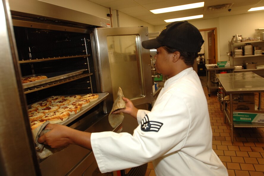 MINOT AIR FORCE BASE, N.D. -- Senior Airman Shameka Risch, 5th Services Squadron, handles a tray of hot pizzas at the Flight Kitchen Tuesday.The Flight Kitchen supports the Airmen who work on the flight line who do not have time to eat at other dining establishments on base. (U.S. Air Force photo by Airman 1st Class Cassandra Butler)