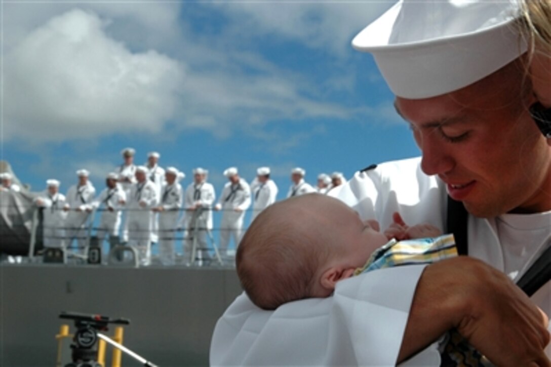 A U.S. Navy sailor holds his child for the first time after returning to Pearl Harbor, Hawaii, from a six-month deployment on board the guided missile destroyer USS Russell, Sept. 5, 2006.  The Russell was part of the USS Abraham Lincoln Carrier Strike Group.  