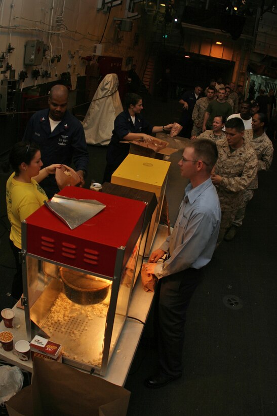 ABOARD USS PELELIU (LHA 5) (Oct. 29, 2008) -- Sailors with the USS Peleliu (LHA 5), Marines with the 15th Marine Expeditionary Unit and "Tigers" line up for popcorn during a Cinema at Sea in the hangar bay aboard USS Peleliu (LHA 5).::r::::n::   Operation Tiger Cruise is a program which brings civilian friends and family of deployed Marines and Sailors for the final leg of a deployment from Pearl Harbor, Hawaii to San Diego, Calif. aboard U.S. Navy vessels.::r::::n::   During Tiger Cruise, Tigers see the day-to-day operations their service members experience during deployment, including eating in the mess decks and sleeping in troop berthing. ::r::::n::    The Camp Pendleton, Calif. based 15th MEU is comprised of approximately 2,200 Marines and Sailors and is a forward deployed force of readiness capable of conducting numerous operations, such as Non-Combatant Evacuation Operations, Humanitarian Assistance Operations and a wide range of amphibious missions. ::r::::n::   The 15th MEU is currently on the final leg of deployment. (Official USMC photo by Cpl. Timothy T. Parish) (Released)::r::::n::::r::::n::