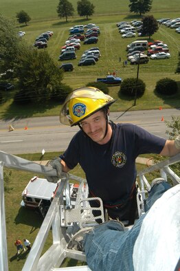 GRISSOM AIR FORCE BASE, Ind. -- Anthony Harper, Grissom Fire Department firefighter, climbs a ladder-truck ladder during the Joint Family Day picnic. Mr. Harper waved to children while displaying the ability of the fire department to reach high into the sky. The ladder truck can reach 75 feet if its ladder is fully extended. (U.S. Air Force photo/SrA. Mark Orders-Woempner)