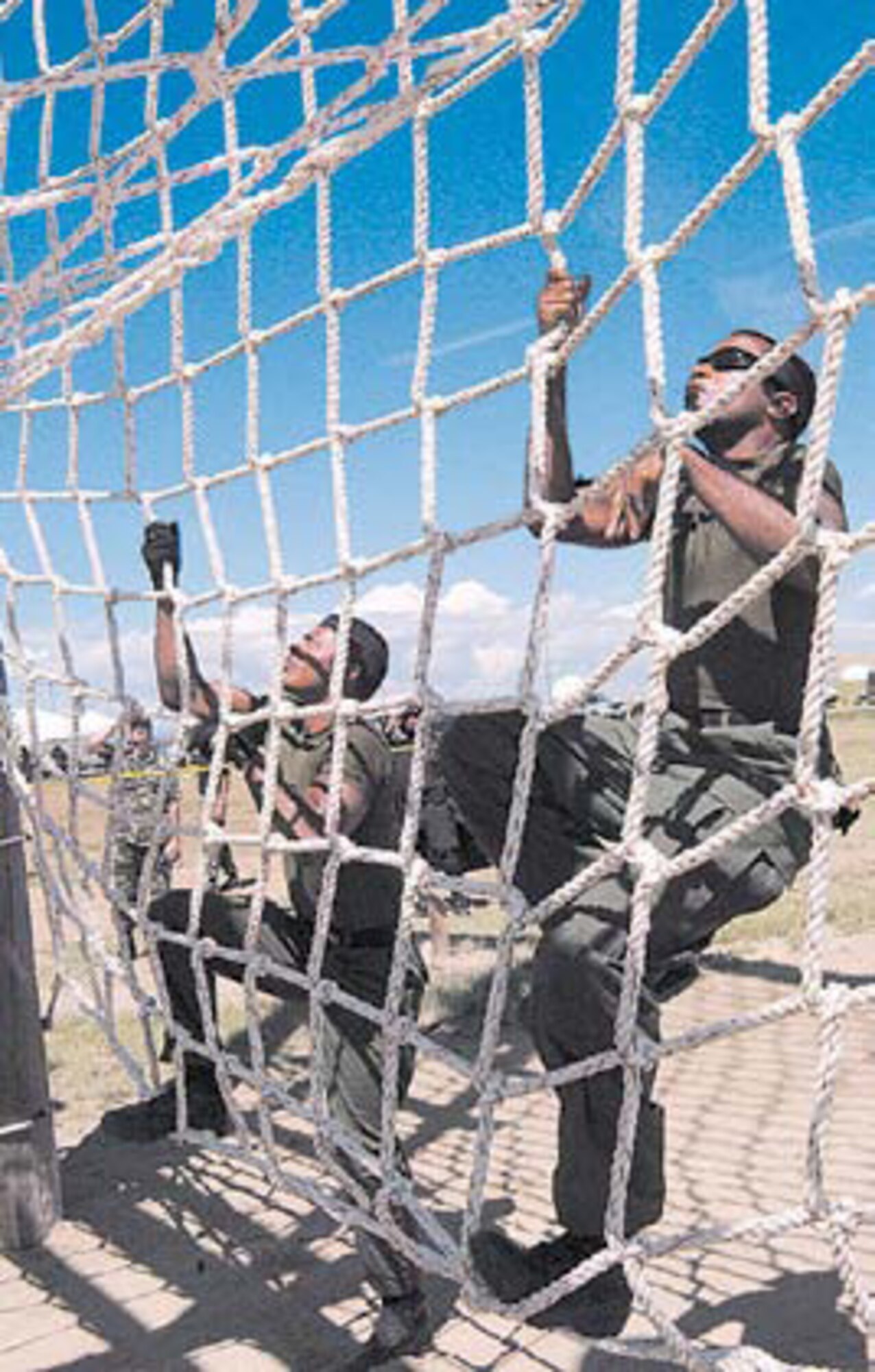 (Left to right) Capt. (DoD Police) Scott Hall and Darrel Worthen climb the web ropes of the tough-man station during the obstacle
course.