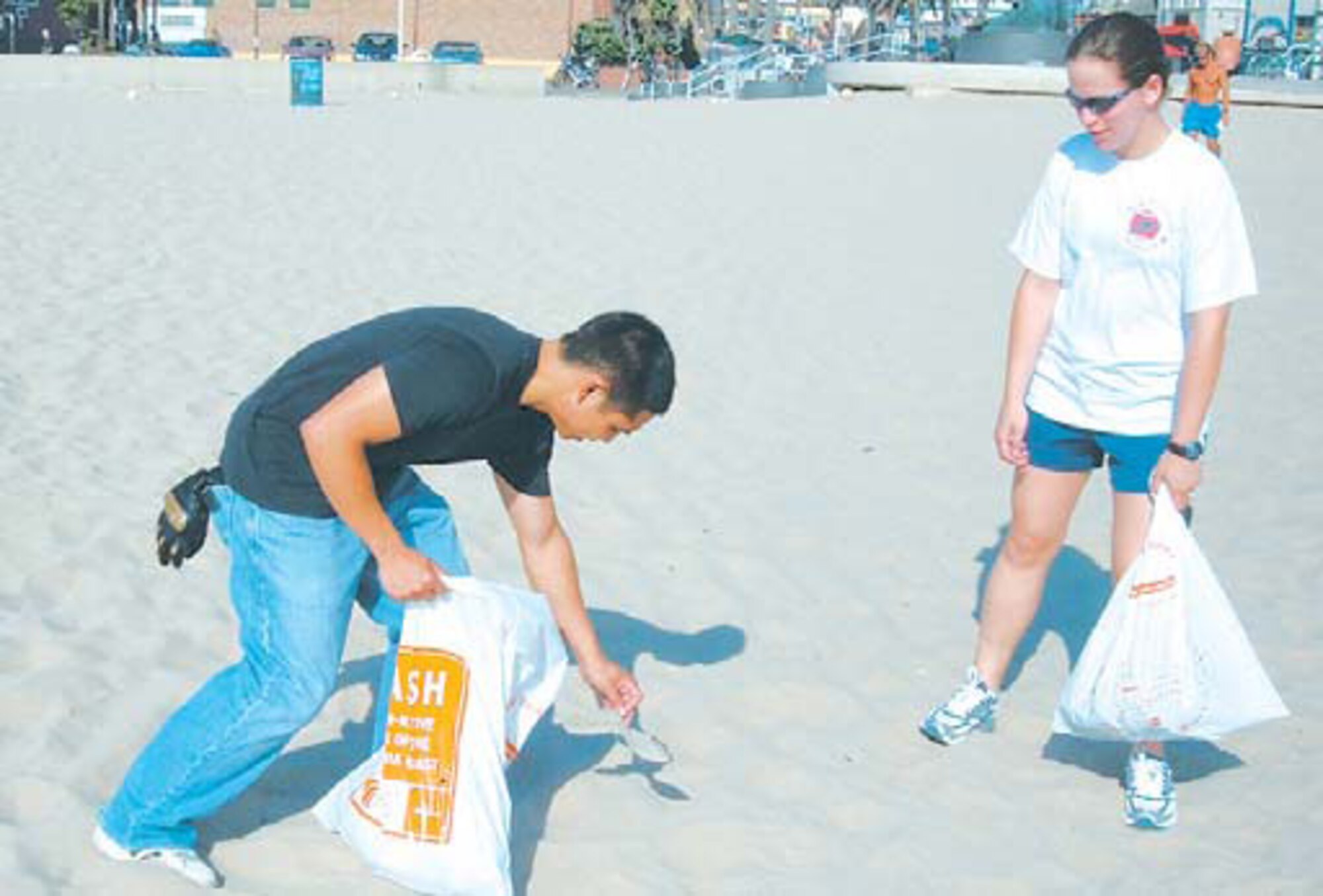 2nd Lt. Rey Jan Garma (left), Space Based Infrared Systems Wing, picks up trash from the sand as 2nd Lt. Margaret Goetz, Global Positioning Systems Wing, assists. They were both part of the SAS class which volunteered to clean the South Bay beaches.