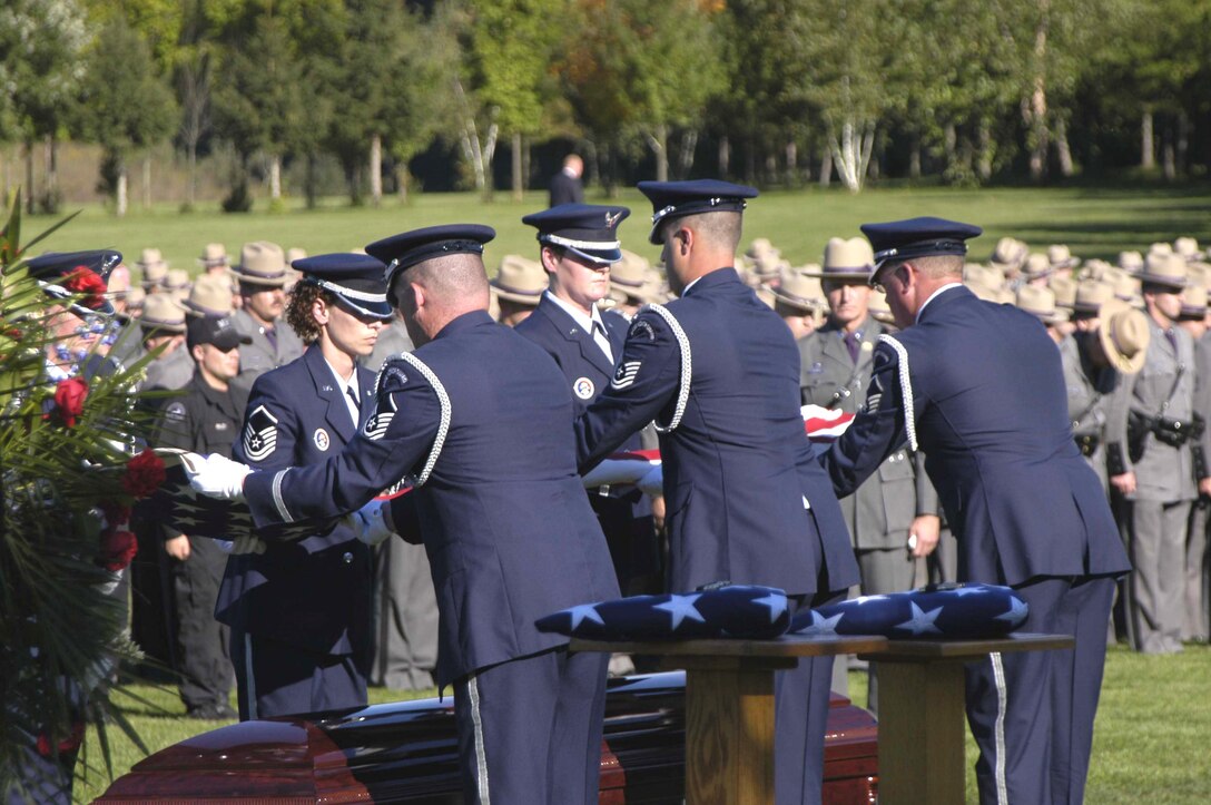 Airmen from the New York Air National Guard's 109th Airlift Wing Honor Guard lift the flag from Master Sgt. Joseph Longobardo's casket during his funeral Sept. 11.  Sergeant Longobardo, a guardsman with the 109th Security Forces Squadron, was a New York State Police officer who was killed in the line of duty Sept. 3 while participating in the manhunt for fugitive Ralph "Bucky" Williams.  More than 100 Airmen from the 109th AW attended his funeral. (U.S. Air Force photo/Master Sgt. Willie Gizara) 