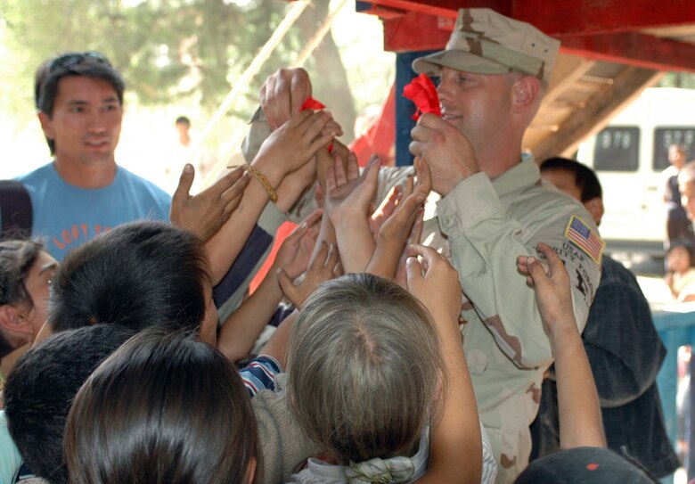 Tech Sgt. Tony Turner, 376th Expeditionary Security Forces, passes out pieces of the ribbon cut during the Oktobersky Village School #1 new children’s playground dedication ceremony June 22. Members from the 376th AEW were on hand to dedicate a new children's playground, built by members of the 376th Expeditionary Security Forces and Civil Engineer Squadrons. Sergeant Turner is deployed from the 917th Security Forces Squadron, Barksdale Air Force Base, La.  (U.S. Air Force Photo/Staff Sgt. Candy Knight)