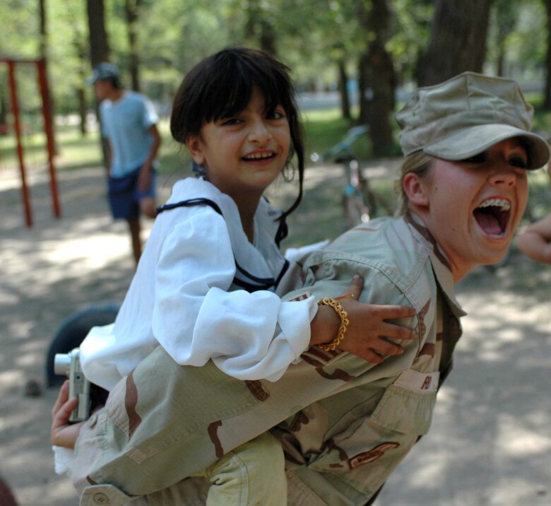 Senior Airman Emily Irby, 376th ESFS, gives a local child a piggyback ride during the dedication ceremony. Members from the 376th AEW were on hand to dedicate a new children's playground, built by members of the 376th Expeditionary Security Forces and Civil Engineer Squadrons. Airman Irby is deployed from the 917th Security Forces Squadron, Barksdale Air Force Base, La.  (U.S. Air Force Photo/Staff Sgt. Candy Knight)