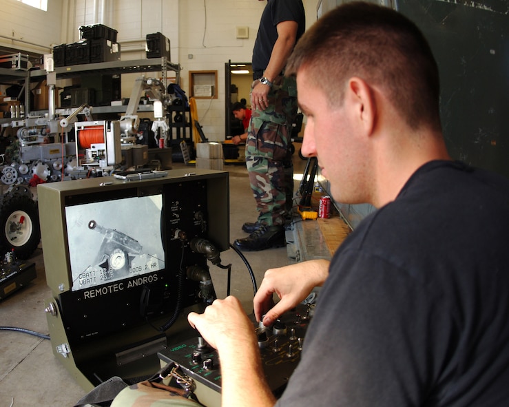 MINOT AIR FORCE BASE, N.D. -- Airman 1st Class Christopher Pringle, 5th Civil Engineer Squadron Explosive Ordnance Disposal, operates a Remotec ANDROS F6A robot to lift a can Sept. 8. EOD can maneuver the robot from a remote screen essentially making the robot the best tool to reach explosive areas to dangerous for military members. (U.S. Air Force photo by Airman 1st Class Joe Rivera) 