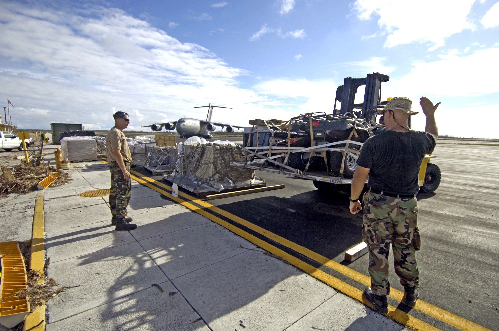Tech. Sgt. Timothy Galunas and Staff Sgt. Ronald White line up pallets on the Wake Island flightline Sept. 12 offloaded from the C-17 Globemaster III in the background. The Airmen are from the 36th Contingency Response Group at Andersen Air Force Base, Guam. They are assisting a 53-person team assessing damage left by Super Typhoon Ioke after it hit the island Aug. 31. (U.S. Air Force photo/Tech. Sgt. Shane A. Cuomo) 
