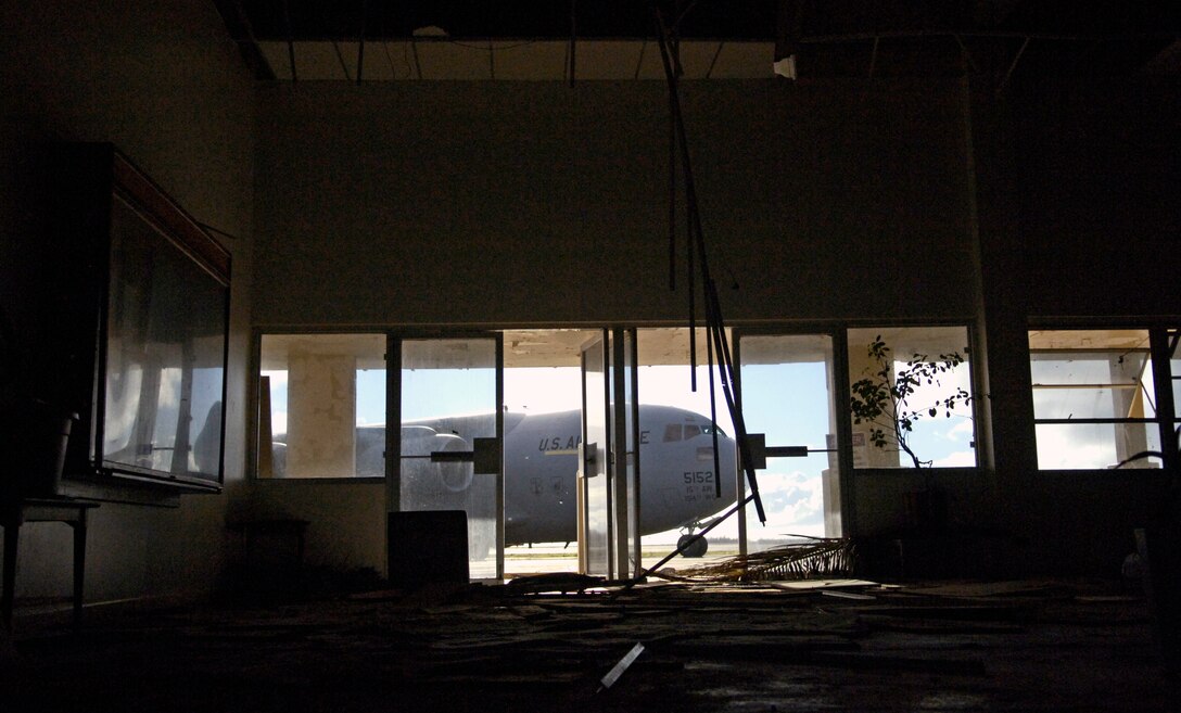 A C-17 Globemaster III is seen through the damaged airfield operations building on Wake Island Sept. 12, 2006. The C-17, from the 535th Airlift Squadron, Hickam Air Force Base, Hawaii is taking the CRG from Andersen Air Force Base, Guam back home. The 36th CRG was the initial assessment team on the island to survey the airfield and determine if aircraft could land after the island was hit by Super Typhoon Ioke Aug 31. (U.S. Air Force photo/ Tech. Sgt. Shane A. Cuomo)