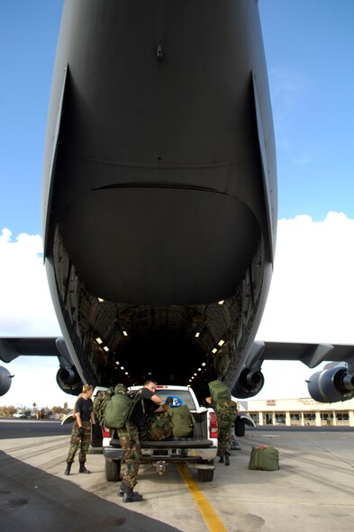Members from the 36th Contingency Response Group load their gear onto a C-17 Globemaster III on Wake Island Sept. 12, 2006. The C-17, from the 535th Airlift Squadron, Hickam Air Force Base, Hawaii is taking the CRG from Andersen Air Force Base, Guam back home. The 36th CRG was the initial assessment team on the island to survey the airfield and determine if aircraft could land after the island was hit by Super Typhoon Ioke Aug 31. (U.S. Air Force photo/ Tech. Sgt. Shane A. Cuomo)