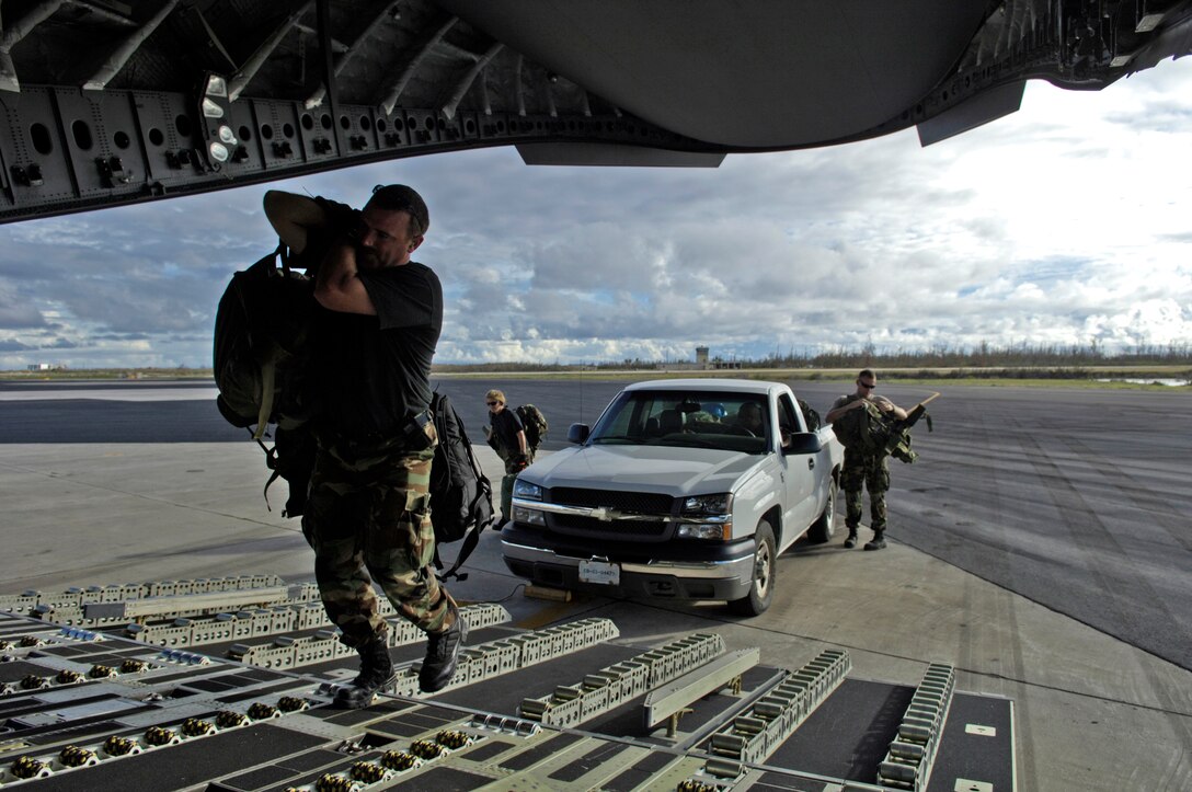Members from the 36th Contingency Response Group load their gear onto a C-17 Globemaster III on Wake Island Sept. 12, 2006. The C-17, from the 535th Airlift Squadron, Hickam Air Force Base, Hawaii is taking the CRG from Andersen Air Force Base, Guam back home. The 36th CRG was the initial assessment team on the island to survey the airfield and determine if aircraft could land after the island was hit by Super Typhoon Ioke Aug 31. (U.S. Air Force photo/ Tech. Sgt. Shane A. Cuomo)