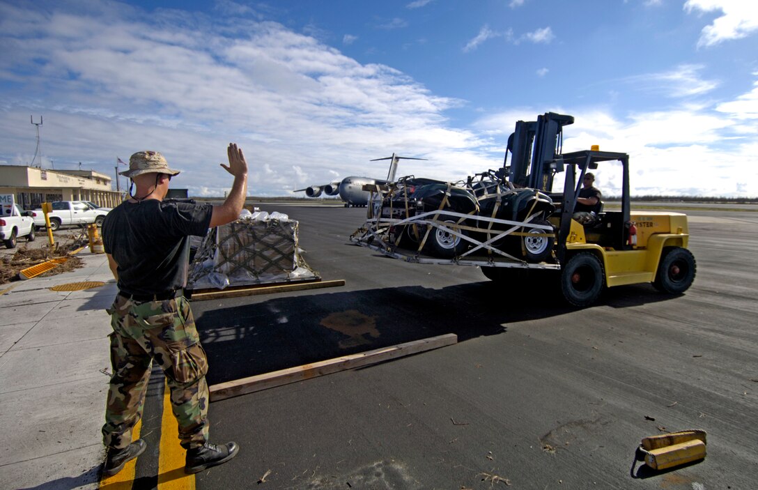 Staff Sgt. Ronald White lines up pallets on the Wake Island flightline Sept. 12, 2006 offloaded from the C-17 Globemaster III in the background. SSgt. White is from the 36th Contingency Response Group at Andersen Air Force Base, Guam. They are assisting a 53-person team assessing damage left by Super Typhoon Ioke after it hit the island Aug. 31. (U.S. Air Force photo/Tech. Sgt. Shane A. Cuomo)
