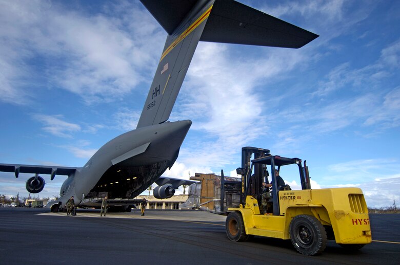 Airmen from the 36th Contingency Response Group at Andersen Air Force Base, Guam, unload a C-17 Globemaster III at Wake Island Sept. 12. The C-17, from the 535th Airlift Squadron at Hickam Air Force Base, Hawaii, brought a 53-person team to assess damage left by Super Typhoon Ioke after it struck the island Aug. 31. (U.S. Air Force photo/Tech. Sgt. Shane A. Cuomo) 
