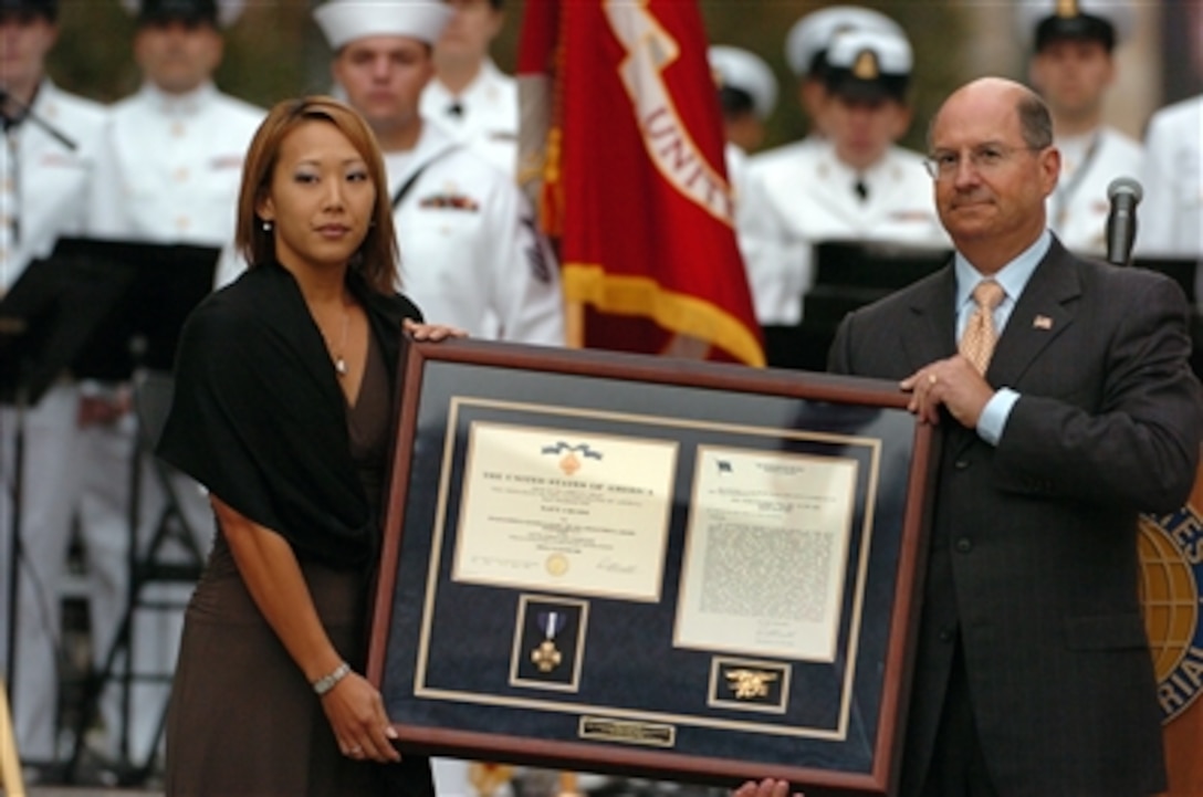 Secretary of the Navy Dr. Donald C. Winter presents the Navy Cross to the wife of Petty Officer 2nd Class (SEAL) Matthew G. Axelson during a ceremony at the Navy Memorial in Washington, D.C., on Sept. 13, 2006. The wife of Petty Officer 2nd Class (SEAL) Danny P. Dietz was also presented the Navy Cross. Both sailors were killed during a mission to locate a high value anti-coalition militia leader in Asadabad, Afghanistan in June 2005. 