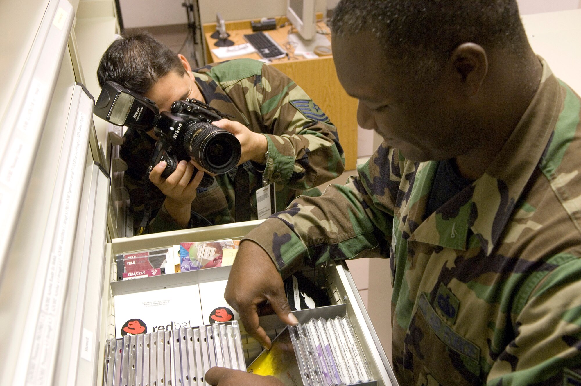 Tech. Sgt. Cecilio Ricardo photographs Tech. Sgt. Kevin Johnson inventorying software at the Air Force News Agency in San Antonio. On-the-job photos and stories of Airmen at work worldwide will be posted on the Air Force Link Web site all day Sept. 18 as the service commemorates its 59th birthday. Photos and stories will be updated throughout the day. (U.S. Air Force photo/Master Sgt. Jack Braden)