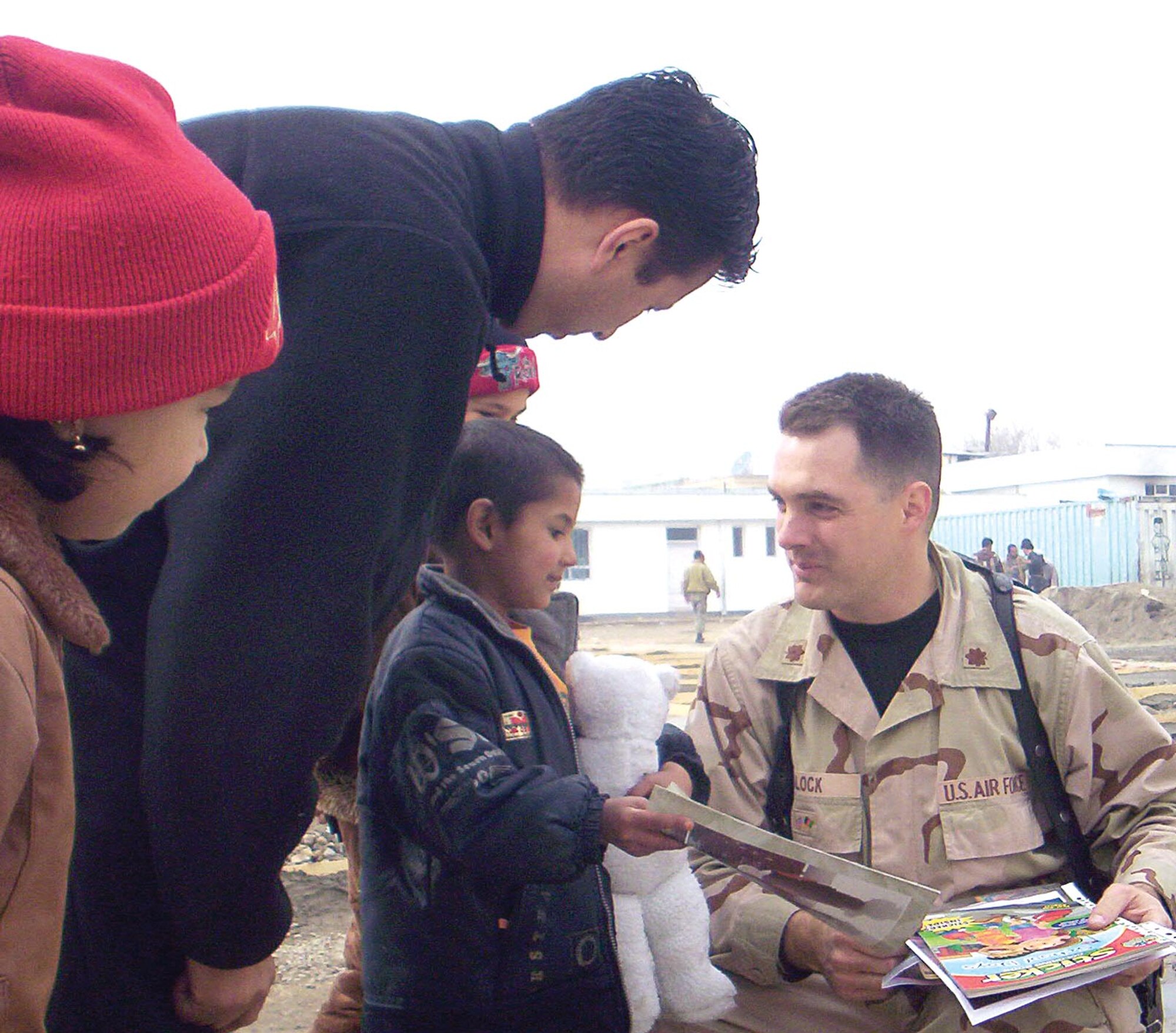 Operations Officer Maj. Jay Block, Office of Security Cooperation-Afghanistan strategic reform division, gives Berheska, an Afghani orphan, coloring books during a visit to the Alauddin orphanage. (Courtesy photo)
