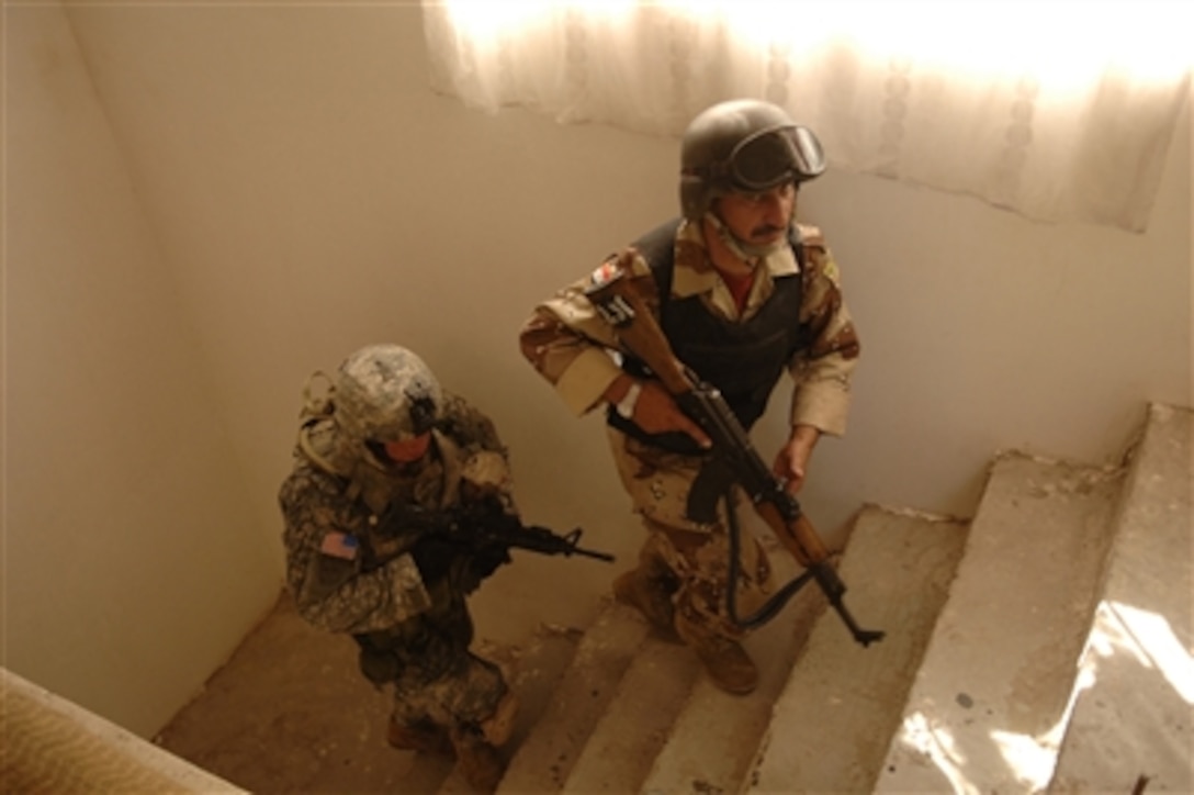 U.S. Army Sgt. Partyka (left) and an Iraqi army soldier climb a flight of stairs as they conduct a combined cordon and search mission in Baghdad, Iraq, on Sept. 10, 2006.  Partyka is attached to Bravo Company 2nd Battalion, 1st Infantry Regiment.  