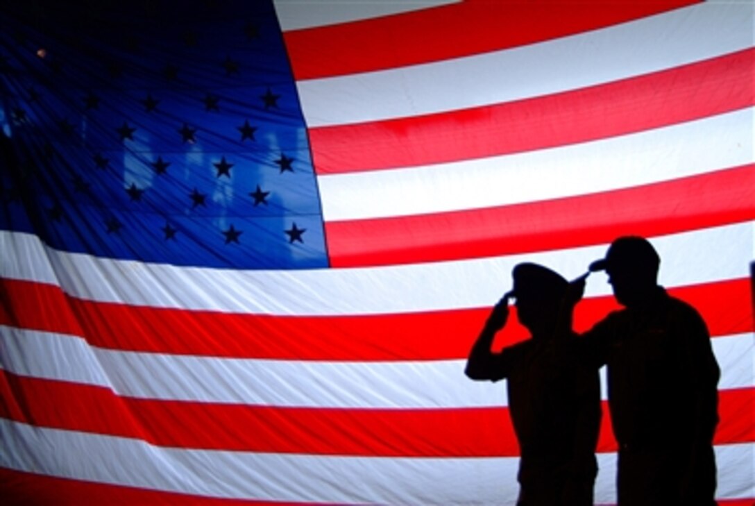 U.S. Navy Cmdr. Marlin C. Anthony, left, commanding officer of the dock landing ship USS Harpers Ferry, and  Command Master Chief Derryll L. Brandt salute as the colors are paraded during a chief petty officer pinning ceremony held in the ship's well deck in Sasebo, Japan, Sept. 15, 2006. 