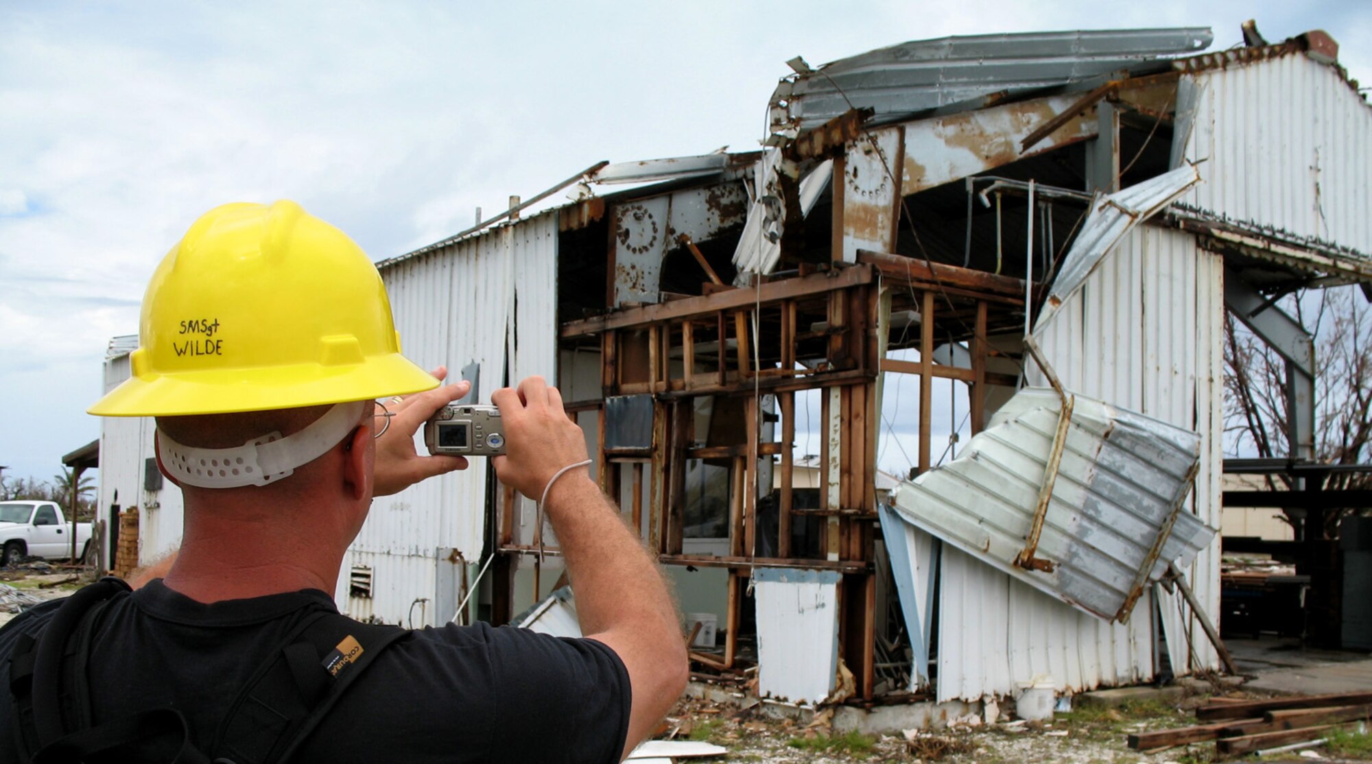 Senior Master Sgt. John Wilde snaps a photo of a damaged building for documentation at Wake Island Sept 15. Sergeant Wilde is part of a damage assessment team deployed to the atoll from the 15th Airlift Wing at Hickam Air Force Base, Hawaii. The team was sent to estimate the cost of repairs to the island after Super Typhoon Ioke touched down Aug 31. (U.S. Air Force photo/Tech. Sgt. Chris Vadnais)