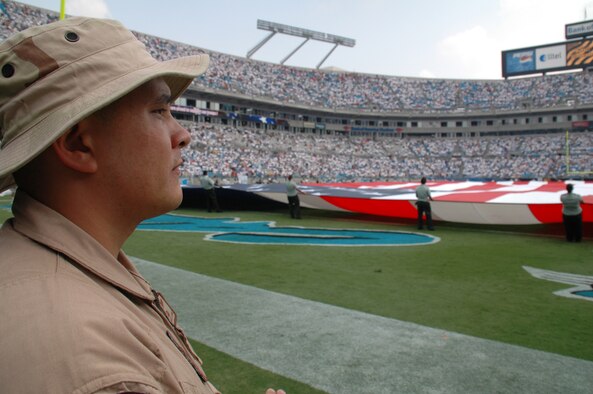 Tech. Sgt. Michael Lang a reservist from the 317th Airlift Squadron, Charleston AFB, S.C., watches as a flag is stretched across the field at the Bank of America Stadium in Charlotte, N.C.  Lang was part of an aircrew consisting of members from each flying squadron in the wing flew a fly-by in a C-17 Globemaster III, for the Carolina Panthers’ season opener on Sept. 10, 2006. (Photo by Capt. Wayne Capps, USAFR)