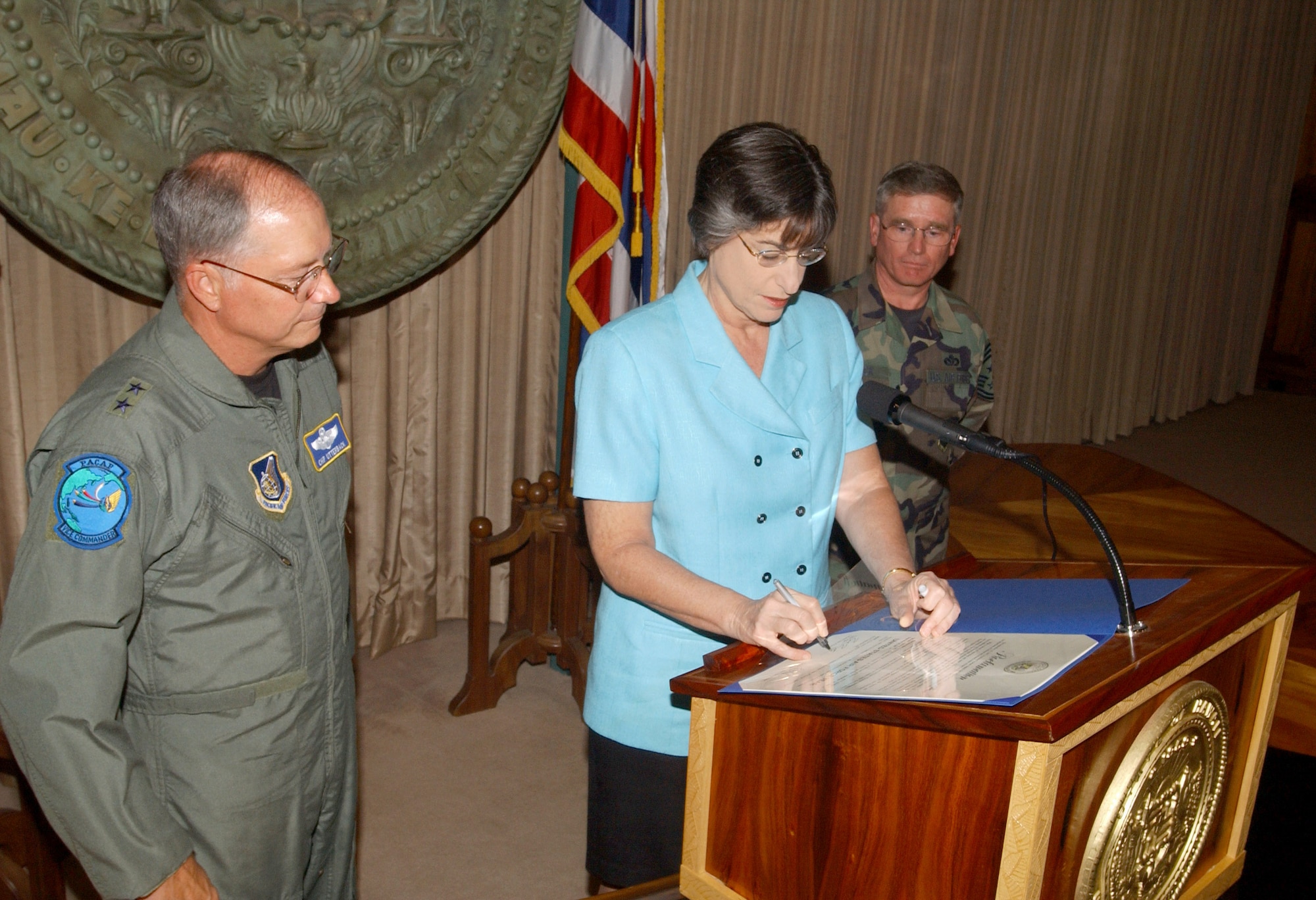Maj. Gen. Loyd S. "Chip" Utterback (left), Pacific Air Forces deputy commander, and Chief Master Sgt. James LeVack, 15th Airlift Wing command chief master sergeant, watch as Hawaii Governor Linda Lingle signs a proclamation designating Sept. 18, 2006, to Sept. 18, 2007, as "United States Air Force Year in Hawaii." The proclamation honors the traditions, heritage and Airmen of the U.S. Air Force. There are more than 10,000 active duty, guardsmen, reservists and Air Force civilians working in Hawaii. (U.S. Air Force photo/Oscar A. Hernandez)
