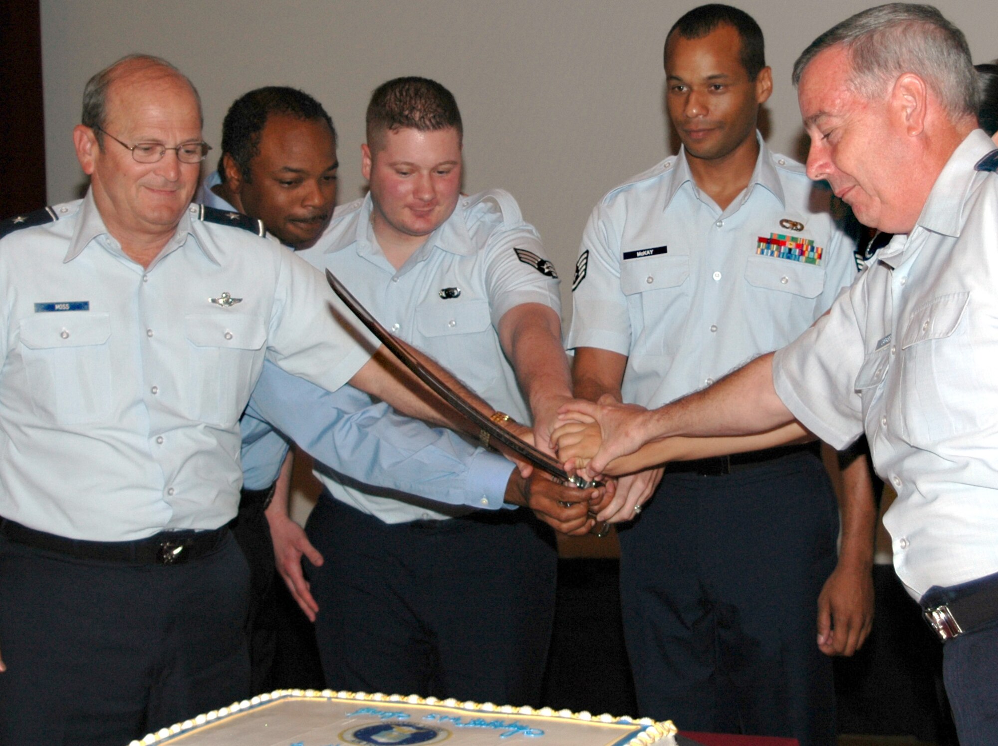 Members of Team Keesler join hands as they cut the cake commemorating the Air Force's 59th birthday, during a ceremony here at Keesler Air Force Base, Miss.  On Sept. 18, 1947 Harry S. Truman, 33rd president, established the Air Force after lessons learned from World Wars I and II.  Celebrating the event from left to right: Brig. Gen. Richard Moss, commander, 403rd Wing; retired Chief Master Sgt. Adrien Augustine representing retired veterans; Senior Airman Jake Gard representing Air National Guardsmen;  Staff Sgt. Shelby McKay, 41st Aerial Port Squadron, representing Air Force Reservists; and Brig. Gen. Paul Capasson, 81st Training Wing commander.  Other Team Keesler representatives not pictured are: 1st Lt. Naomi Henign, 336th Training Squadron; Ms. Carol Enling, representing the 81st Transportation Squadron; Airman Veronica Torres, representing the 81st Dental Squadron. 