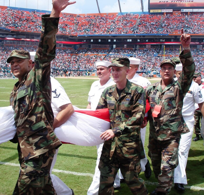 (Left to right in camouflage) Staff Sgt. Armstrong Gil, Senior Airman David Dey and Tech. Sgt. Terry Troup were some of the 50 reservists from Homestead Air Reserve Base, Fla. to represent the Air Force Reserve during opening ceremonies of the Dolphins first home game on Sep. 17. The reservists joined about 300 soldiers and sailors in a tribute to the US Armed Forces, unfurling a field-size American flag. (Air Force photo by Jake Shaw)