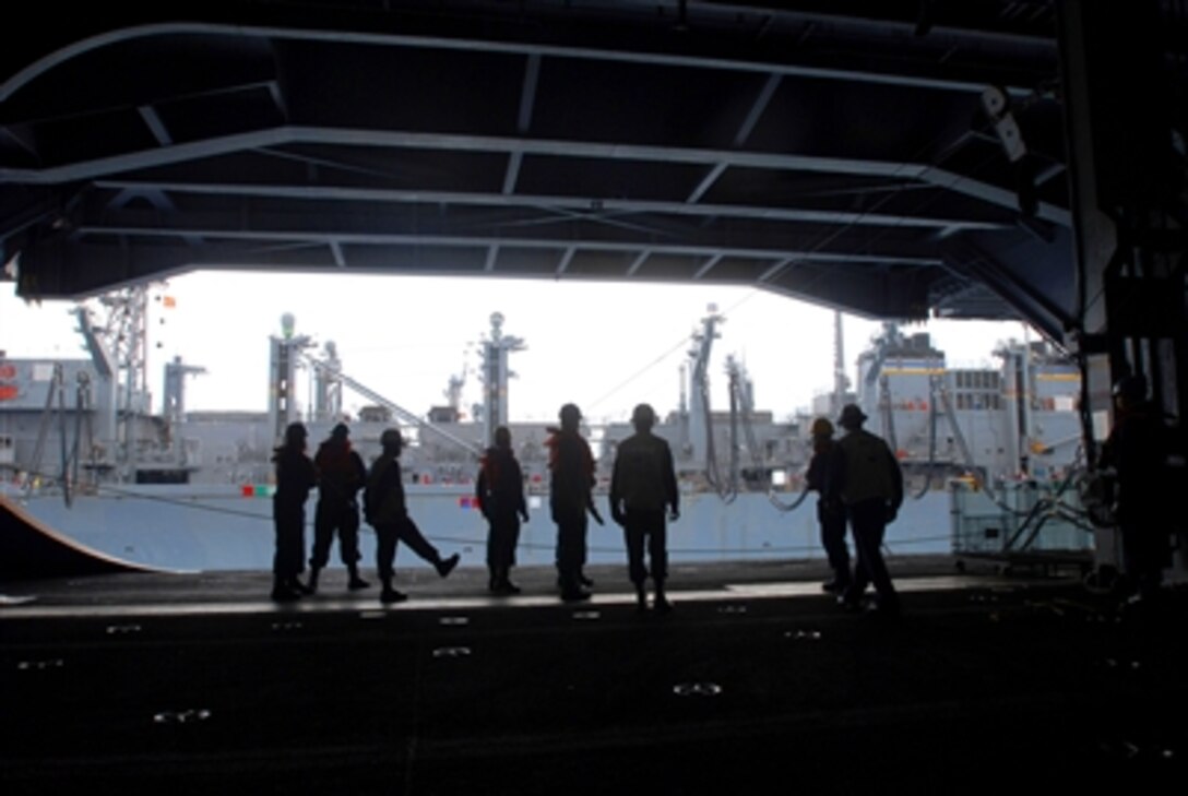 U.S. Navy crew members stand by in the hangar bay aboard the nuclear-powered aircraft carrier USS Nimitz during an underway replenishment with the Military Sealift Command fast combat support ship USNS Bridge, Sept. 13, 2006.  