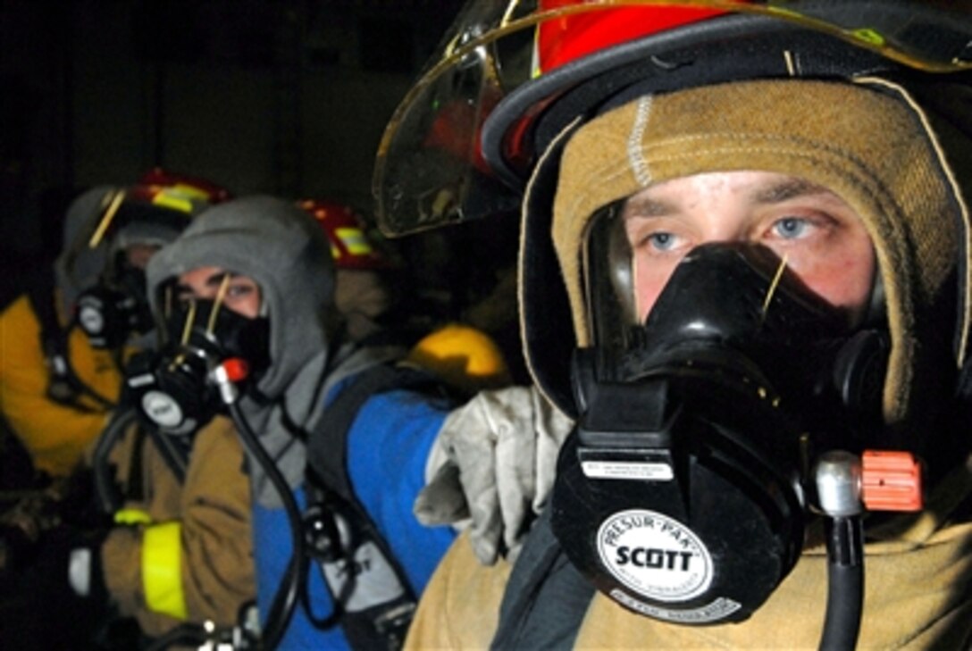 A fire party member awaits orders from the hose team leader to "test agent," before fighting a simulated aircraft fire during a general quarters drill in the hangar bay aboard the Nimitz-class aircraft carrier USS John C. Stennis while under way in the Pacific Ocean, Sept. 17, 2006. 