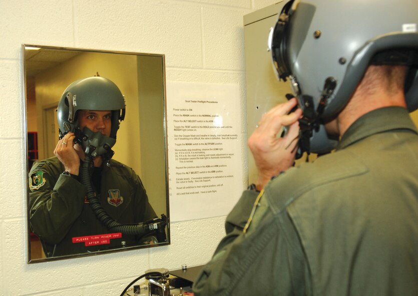 MINOT AIR FORCE BASE, N.D. -- Capt. Nathan Oltmans, 23rd Bomb Squadron, looks in the mirror as he tries on his helmet and uses an oxygen and communication system tester before flying Sept. 19. (U.S. Air Force photo by Airman 1st Class Cassandra Butler)